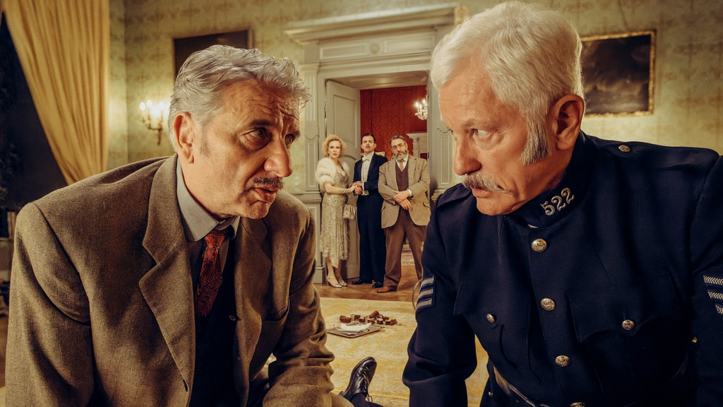 Chief Inspector Francis Lightmyer (Udo Wachtveitl, links vorne) und Constable Ivor Partridge (Miroslav Nemec, rechts vorne) untersuchen Arthur im Kaminzimmer. Lady Bantam (Sunnyi Melles), Charles (Ferdinand Hofer) und Dr. Mallard (Alexander Hörbe, rechts hinten) beobachten sie. | Bild: BR/Bavaria Fiction GmbH/Hendrik Heiden Chief Inspector Francis Lightmyer (Udo Wachtveitl, links vorne) und Constable Ivor Partridge (Miroslav Nemec, rechts vorne) untersuchen Arthur im Kaminzimmer. Lady Bantam (Sunnyi Melles), Charles (Ferdinand Hofer) und Dr. Mallard (Alexander Hörbe, rechts hinten) beobachten sie.