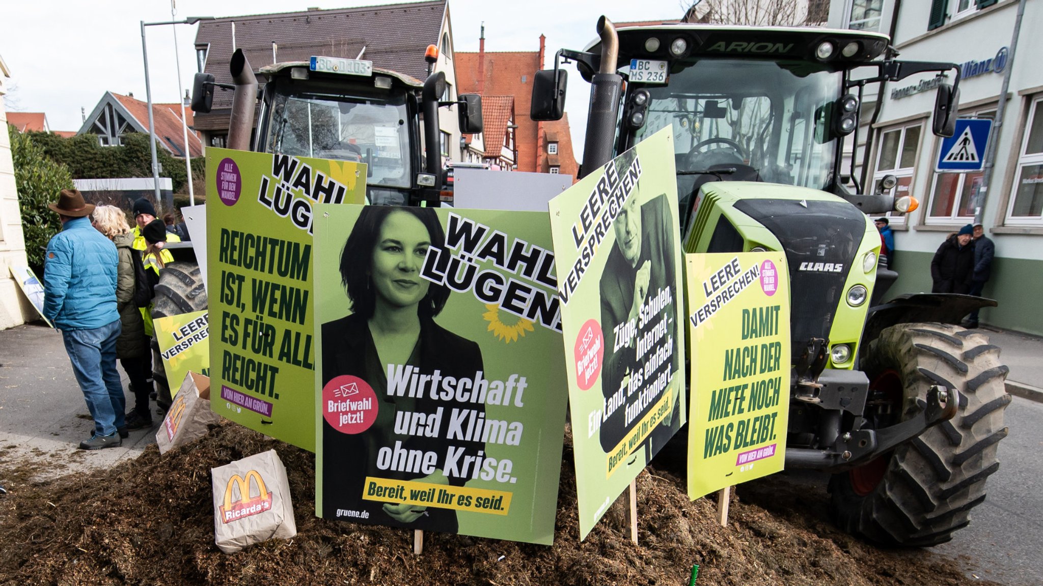 14.02.2024, Baden-Württemberg, Biberach an der Riß: Plakate mit der Aufschrift «Wahl Lügen» stecken während einer Demonstration vor der Stadthalle zum politischen Aschermittwoch der baden-württembergischen Grünen in einem Misthaufen. Foto: Silas Stein/dpa +++ dpa-Bildfunk +++