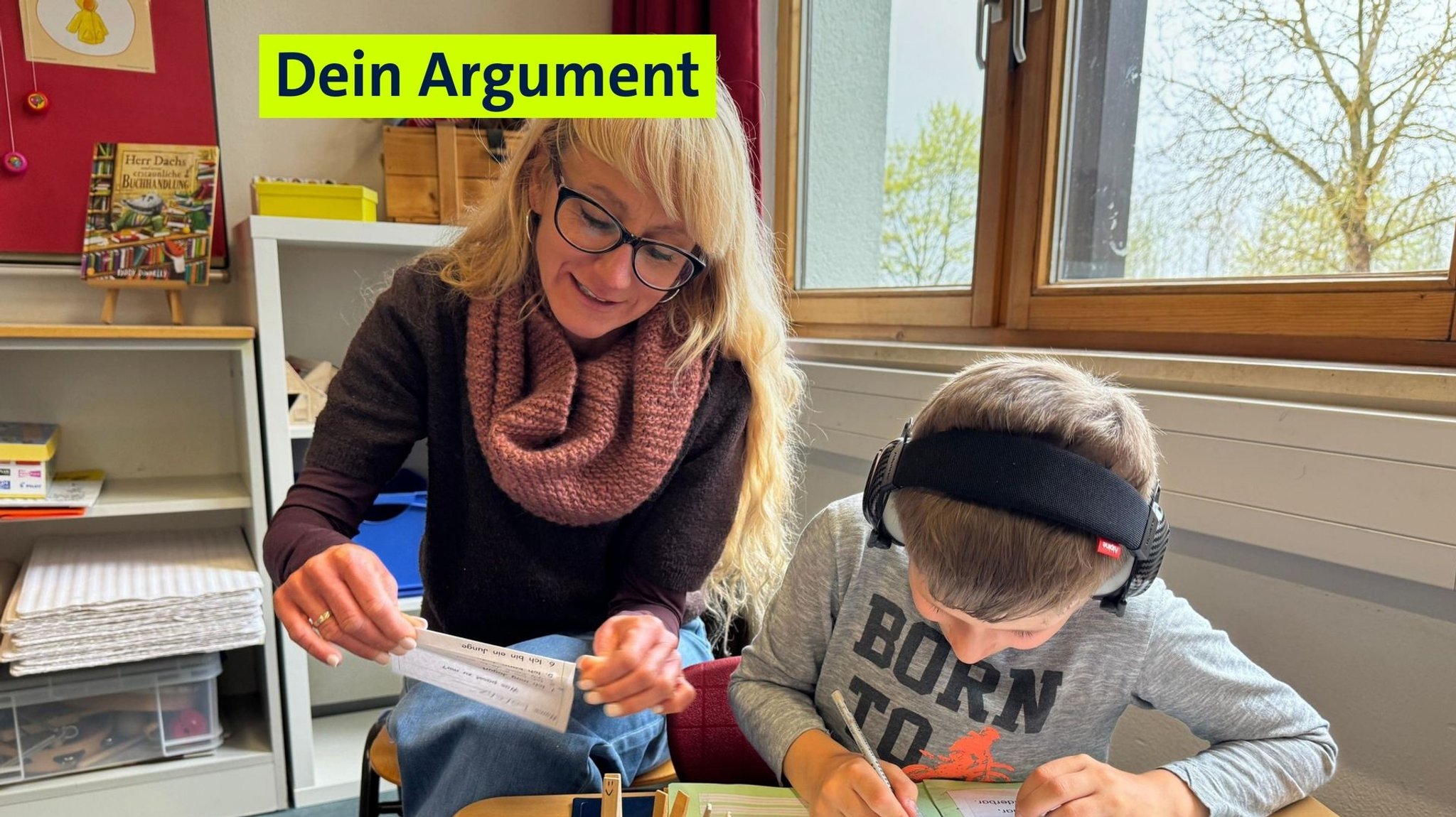 Eine Schulbegleiterin sitzt mit einem Kind an einem Tisch und hilft beim Lernen.