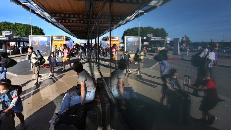 Passagiere spiegeln sich in der verglasten Fassade des Allgäu Airport