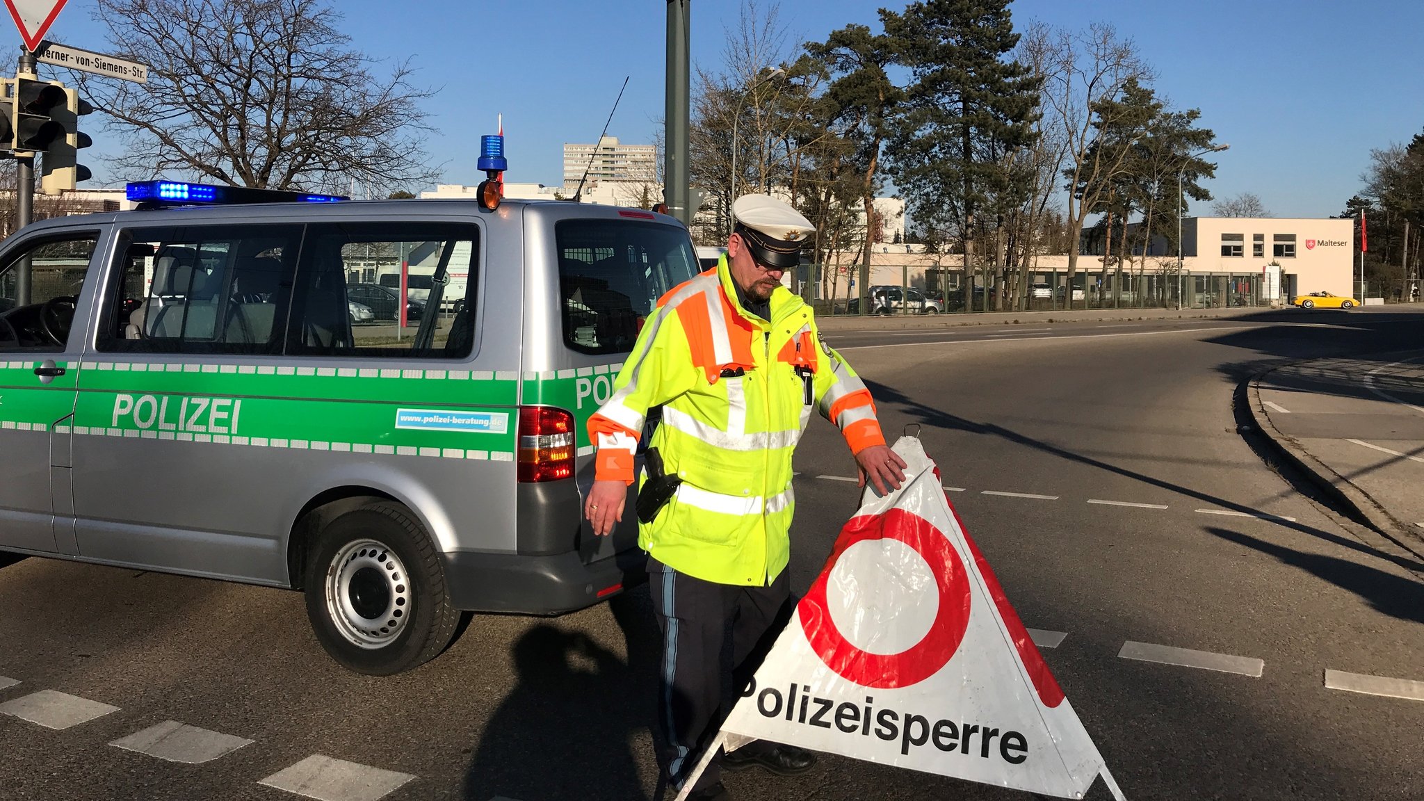 Ein Polizist stellt eine Polizeisperre im Augsburger Univiertel auf (Symbolbild)