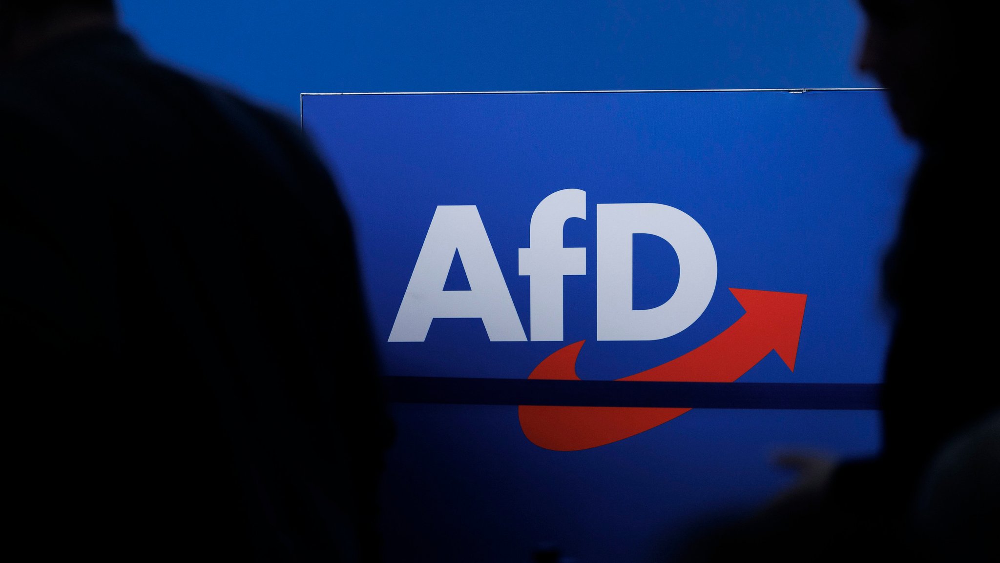 ARCHIV - 28.07.2023, Sachsen-Anhalt, Magdeburg: Delegierte gehen vor dem Parteilogo bei dem AfD-Bundesparteitag in Magdeburg. (zu dpa: «Verfassungsschutz: AfD ist gesichert rechtsextremistisch») Foto: Carsten Koall/dpa +++ dpa-Bildfunk +++