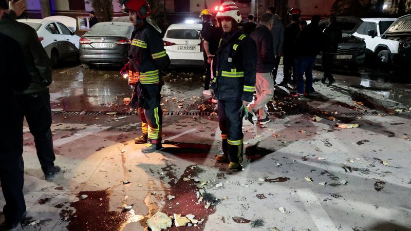 Aufnahme vom 4. März 2026 um 20.43 Uhr: Leute stehen bei heruntergefallenen Trümmerteilen einer Drohne, die ein Gebäude in der Nähe des Flughafens von Erbil getroffen hat. | Bild: REUTERS/Khalid al Mousily Aufnahme vom 4. März 2026 um 20.43 Uhr: Leute stehen bei heruntergefallenen Trümmerteilen einer Drohne, die ein Gebäude in der Nähe des Flughafens von Erbil getroffen hat.