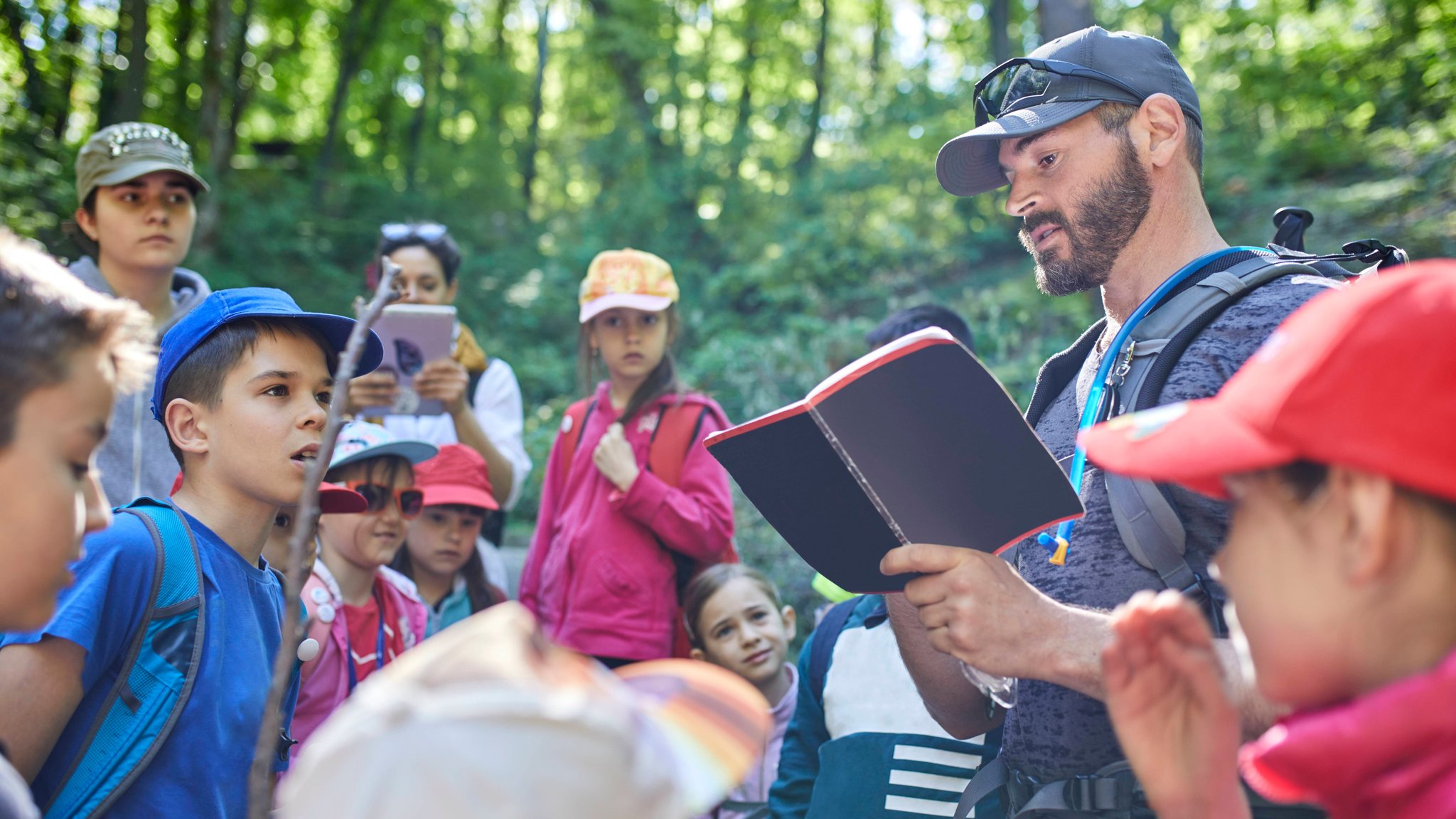 (Symbolbild) Schülerinnen und Schüler mit Lehrer im Wald