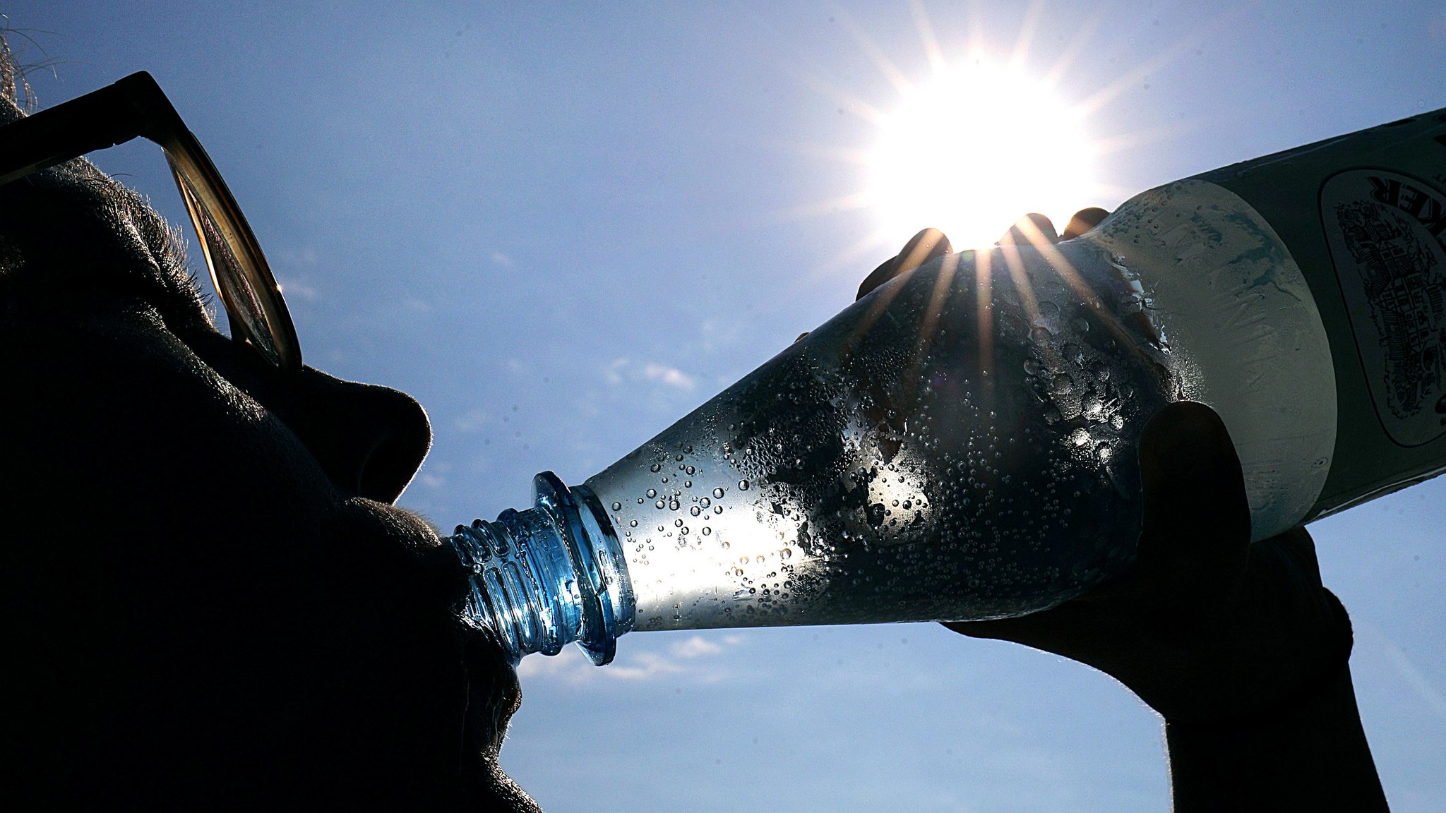 Frau trinkt aus einer Flasche Wasser