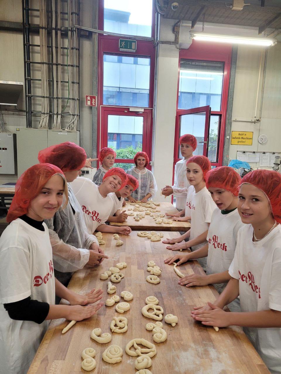 Die ukrainischen Kinder rollen in einer Backstube Teig in Brezen-Form. 