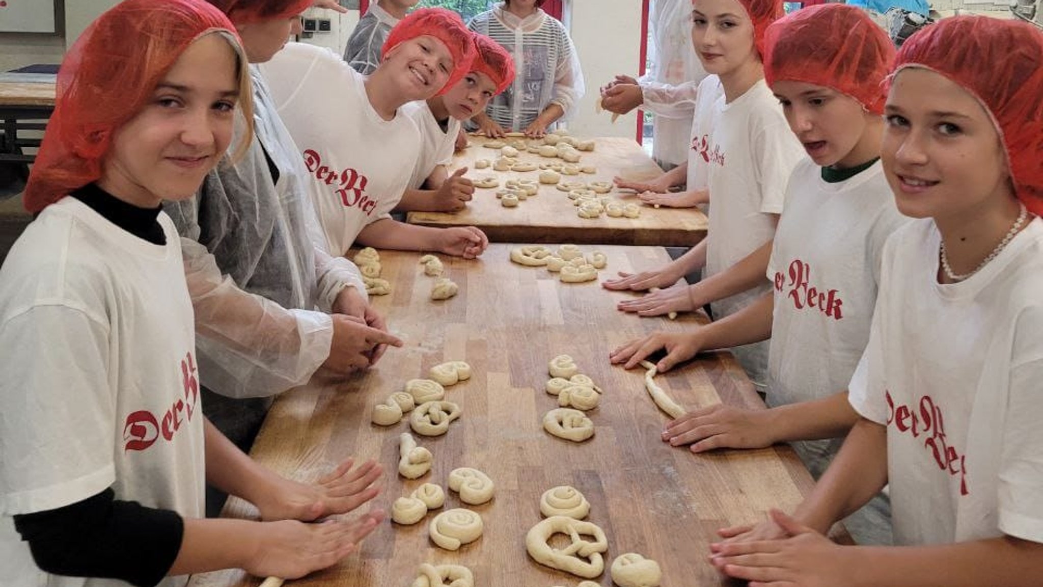 Die ukrainischen Kinder rollen in einer Backstube Teig in Brezen-Form. 