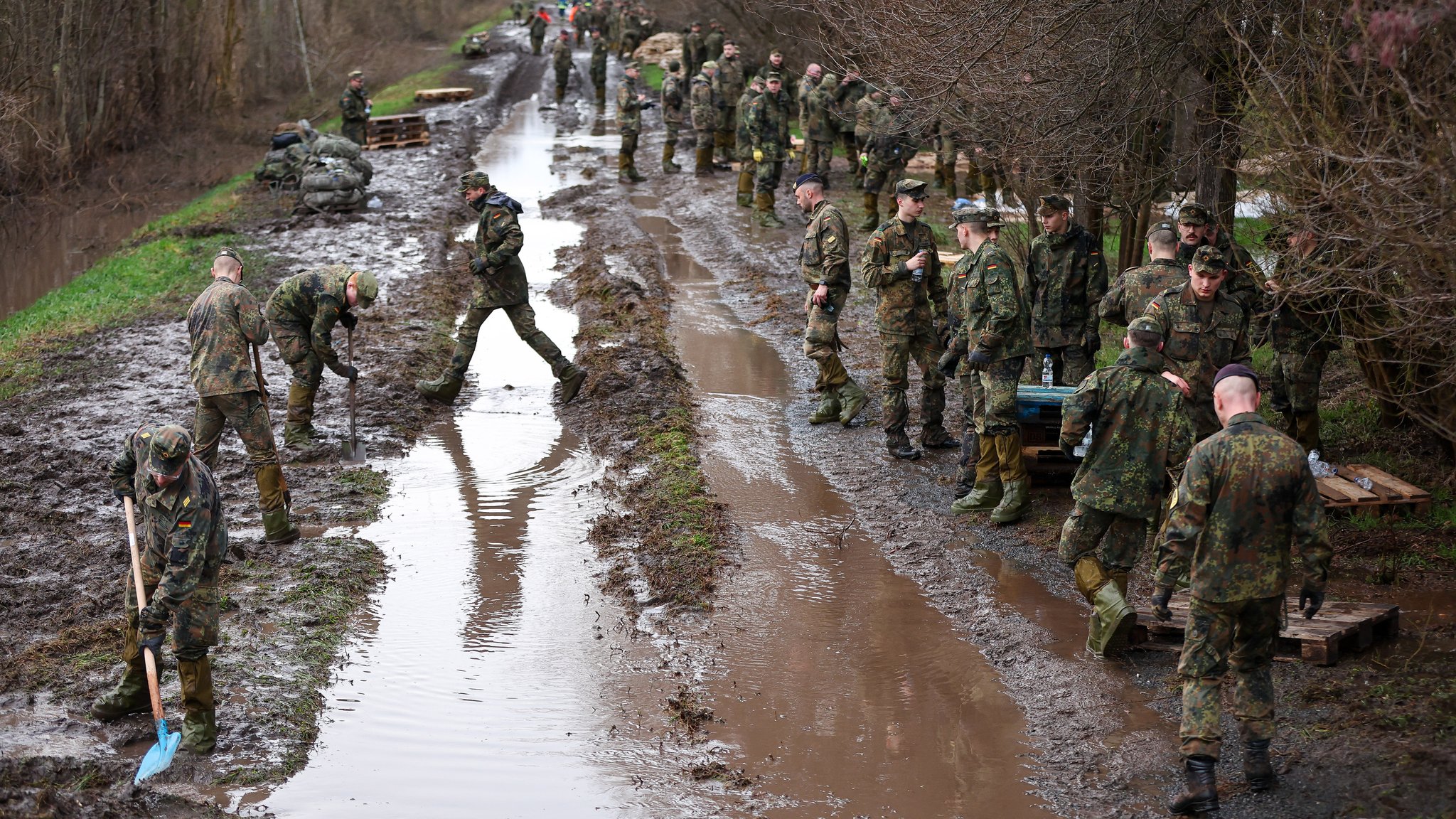 Soldatinnen und Soldaten der Bundeswehr sichern einen Deich an der Helme mit Sandsäcken. 