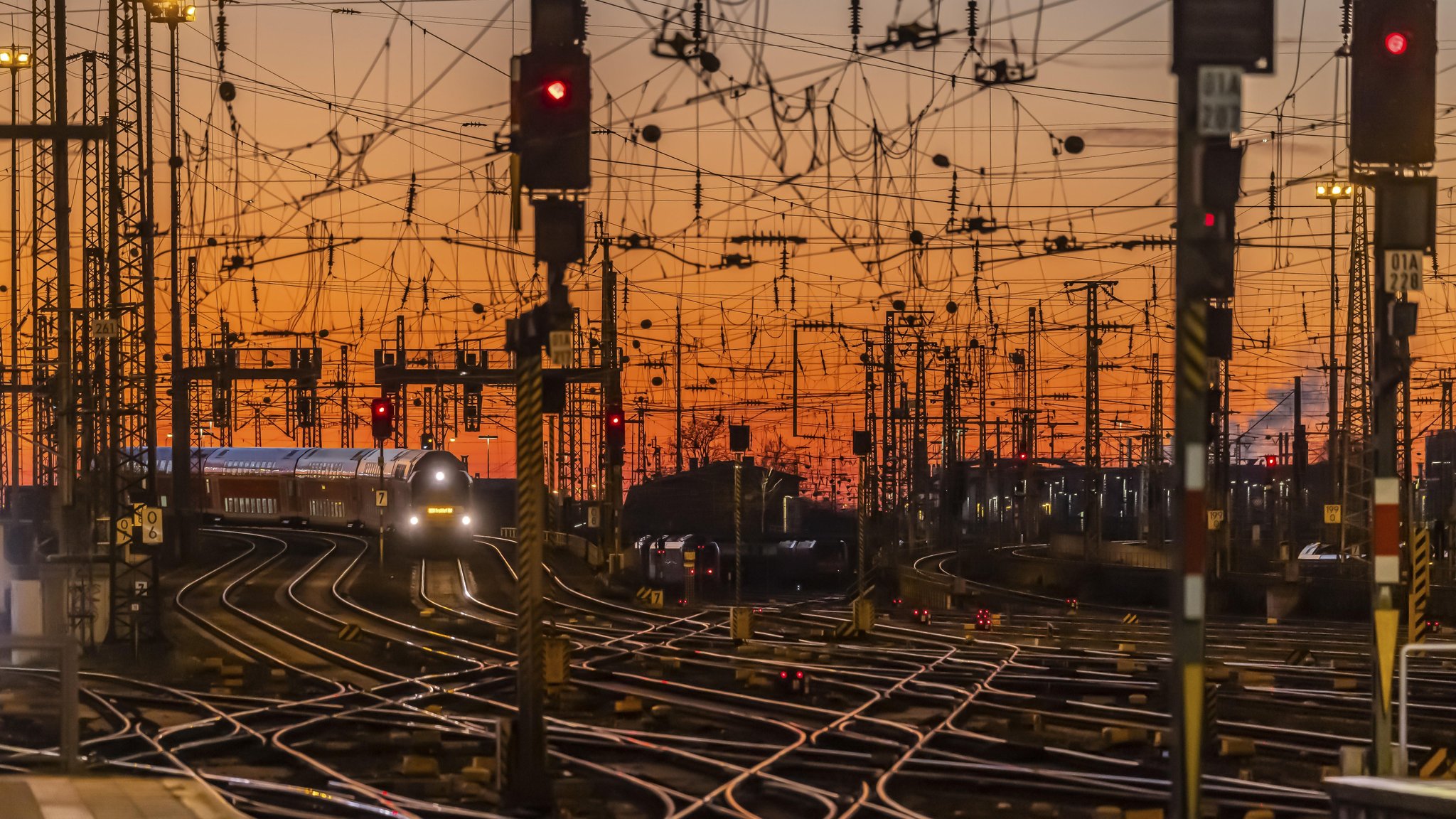 Ein Wirrwarr aus Eisenbahngleisen und Oberleitungen im Abendlicht