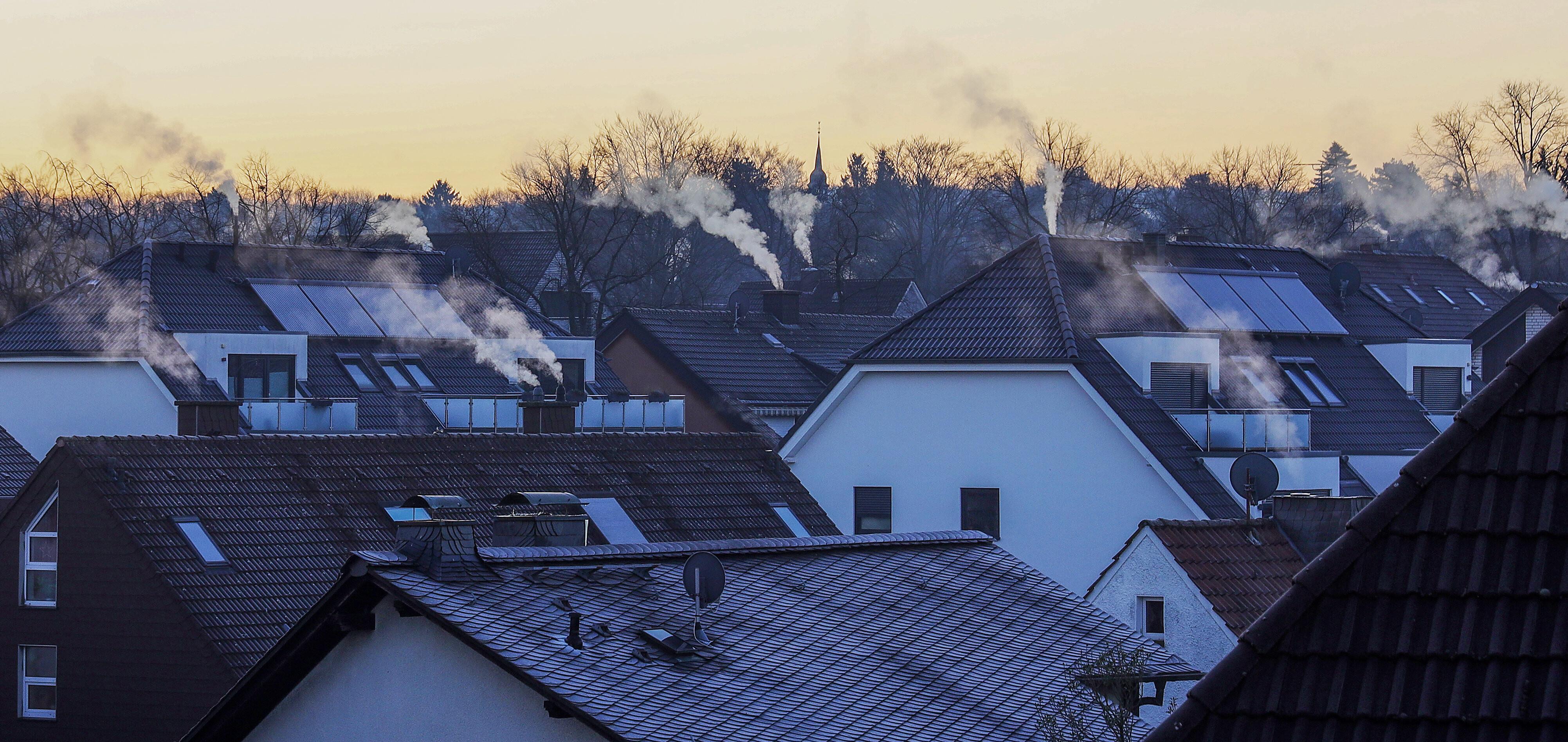 Dächer im Morgengrauen, aus deren Schornsteinen Rauch aufsteigt