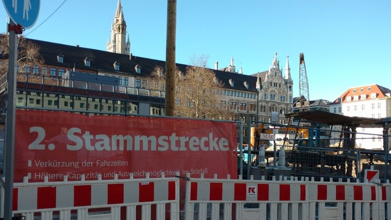 Baustelle zur 2. Stammstrecke am Münchner Marienhof, davor ein rotes Baustellenplakat mit der Aufschrift "2. Stammstrecke"