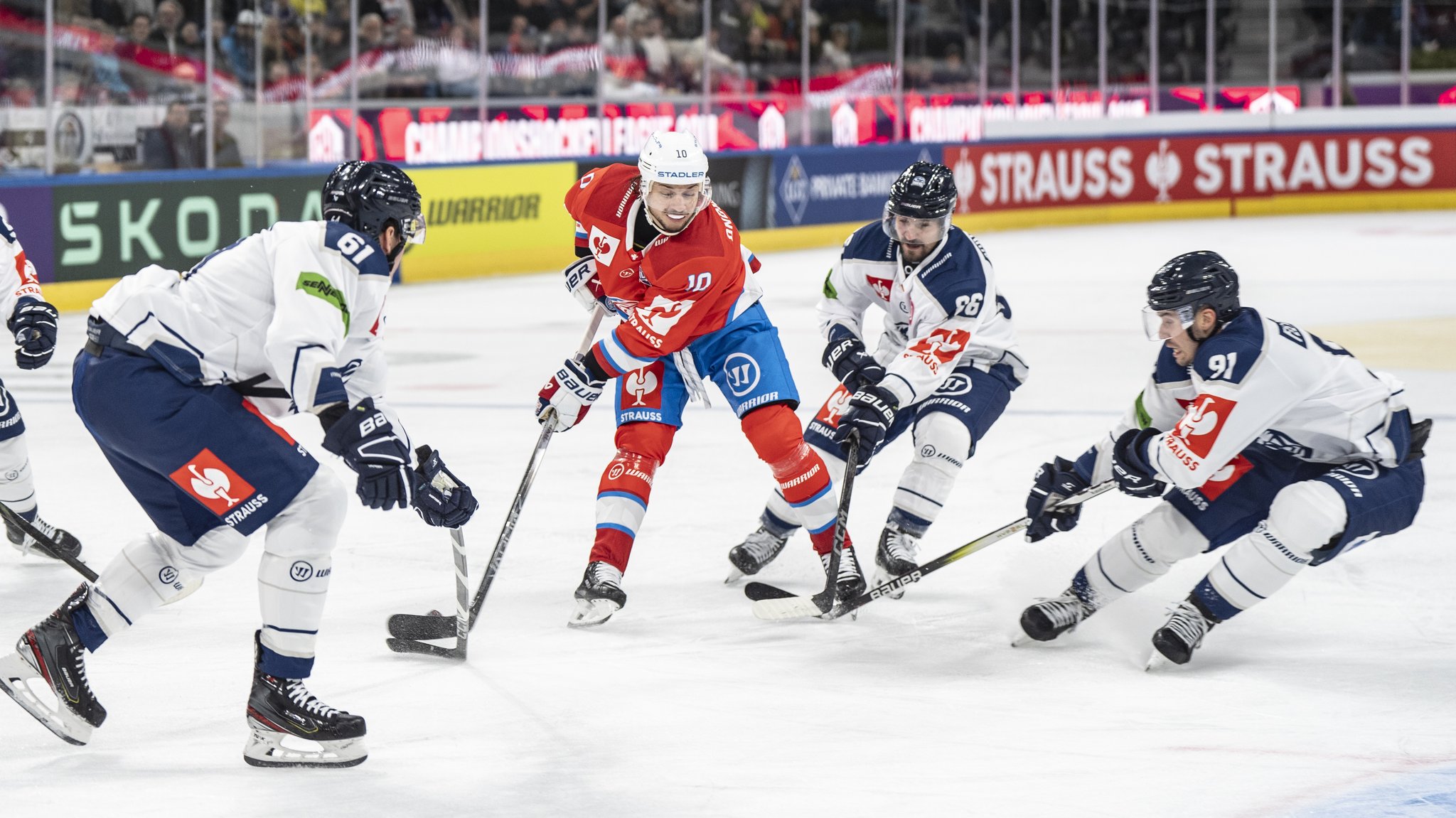 Vier Eishockeyspieler kämpfen auf dem Eis um den Puck. 