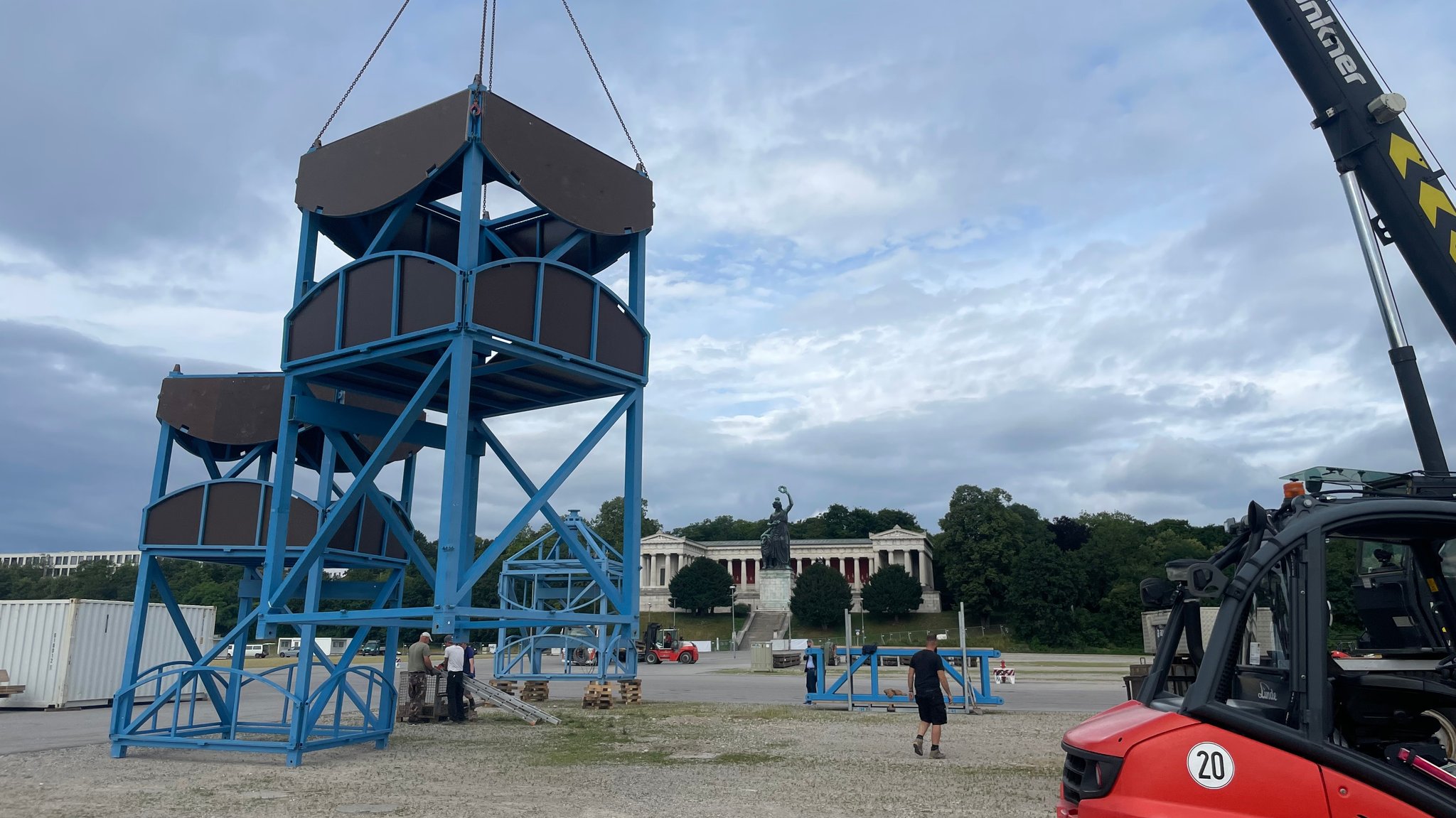 Zu sehen ein Kran, der auf der Theresienwiese Teile für den Löwenbräu-Turm von A nach B befördert