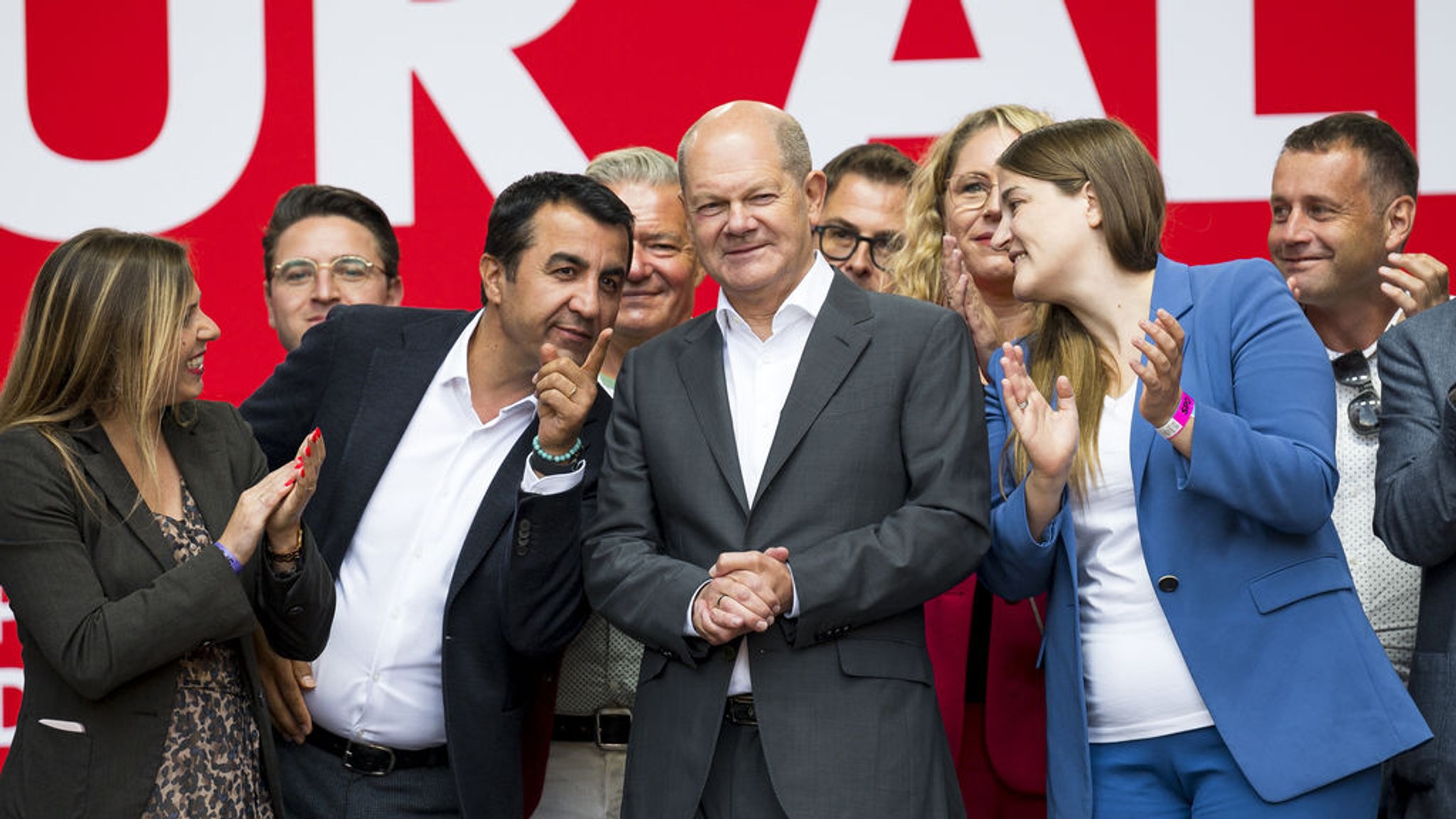 23.09.2023, Bayern, Nürnberg: Arif Tasdelen (3.v.l, SPD) spricht zu Olaf Scholz (M, SPD), Bundeskanzler der Bundesrepublik Deutschland, während das Publikum nach seiner Rede applaudiert. Um ihn herum stehen Mitglieder und Mitgliederinnen der Nürnberg SPD, darunter Ronja Endres (2.v.l, SPD), Vorsitzende der Bayern SPD. Foto: Daniel Vogl/dpa +++ dpa-Bildfunk +++