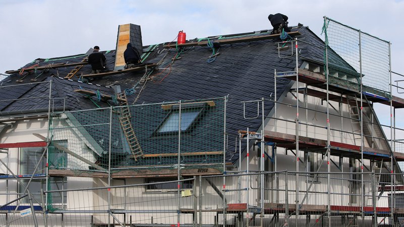 Männer arbeiten am Dach eines Neubaus | Bild: dpa-Bildfunk/Fredrik von Erichsen Männer arbeiten am Dach eines Neubaus