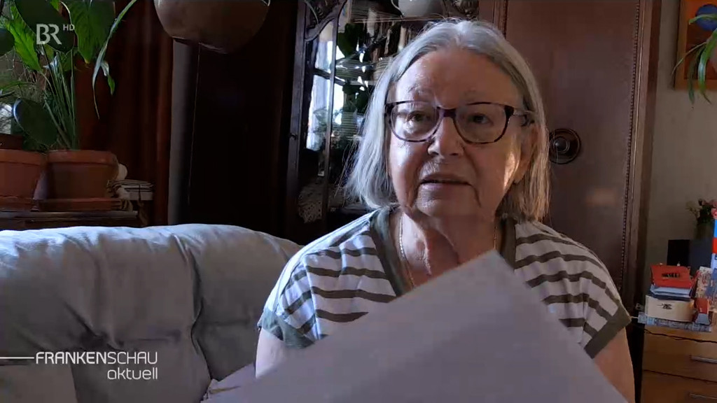 Margarete Rodamer mit einem Stapel Zetteln in der Hand in ihrem Wohnzimmer.