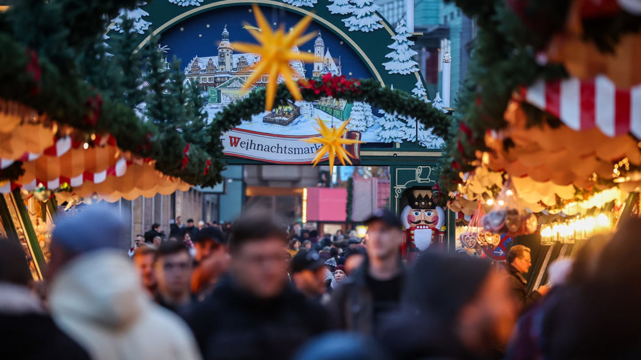 Besucher schlendern über einen Weihnachtsmarkt.