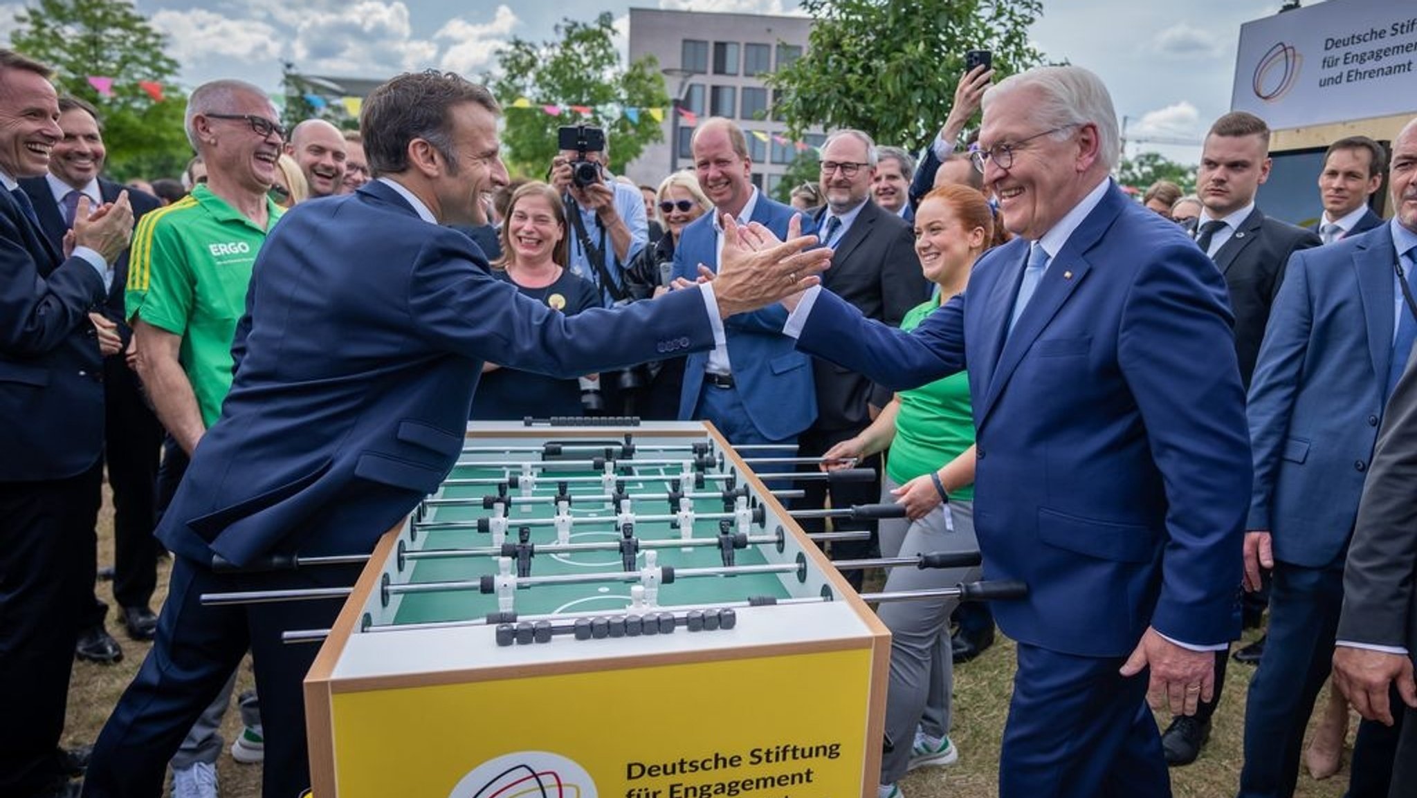 Emmanuel Macron, Präsident von Frankreich, besucht zusammen mit Bundespräsident Frank-Walter Steinmeier das Demokratiefest aus Anlass von 75 Jahren Grundgesetz und sie stehen dabei an einem Tischkicker.