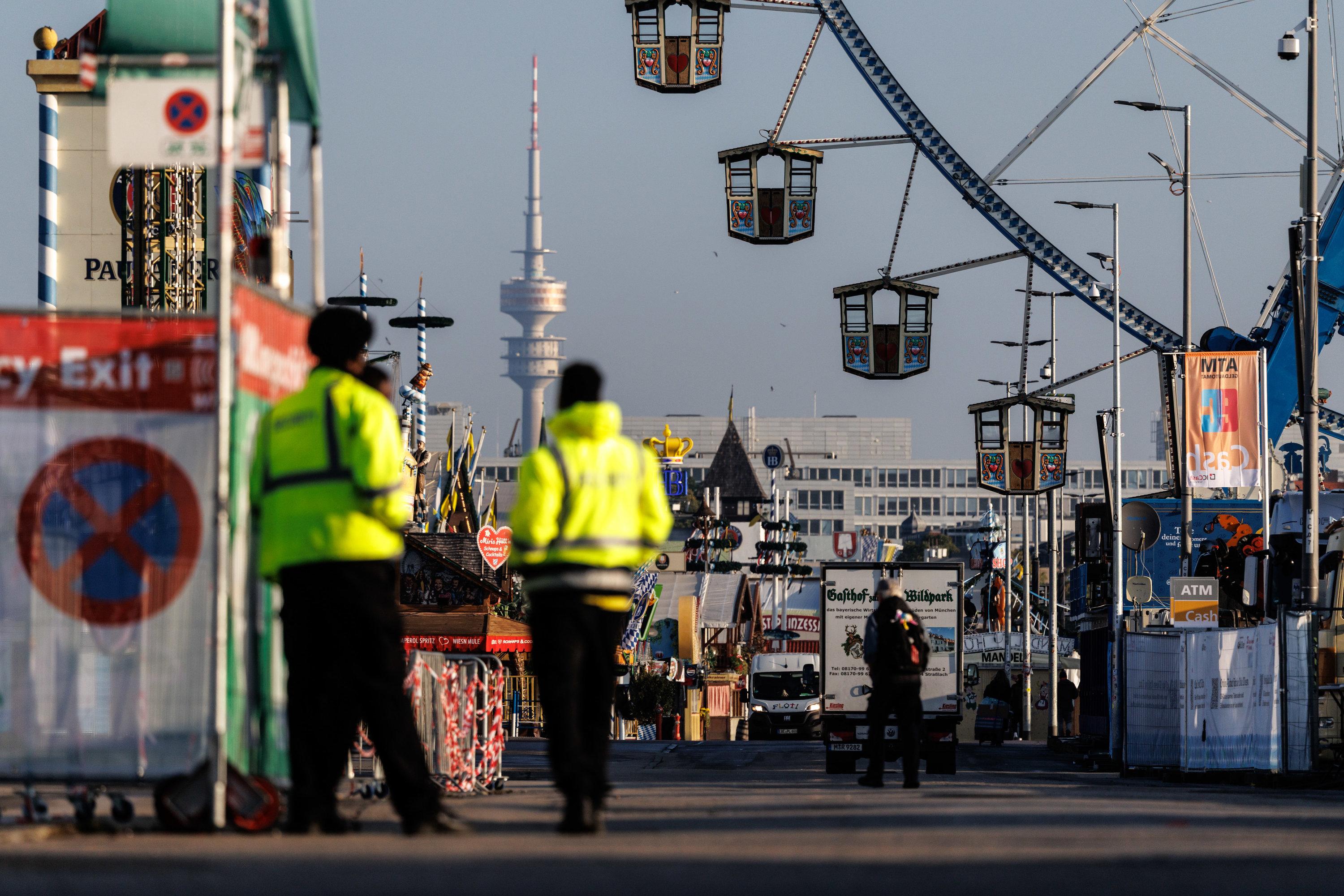 02.10.2025, Bayern, München: Sicherheitspersonal steht am Morgen vor der Öffnung des Oktoberfests für Besucher an einem Eingang vom Oktoberfestgelände, während Mitarbeiter und Zulieferer das Gelände betreten.