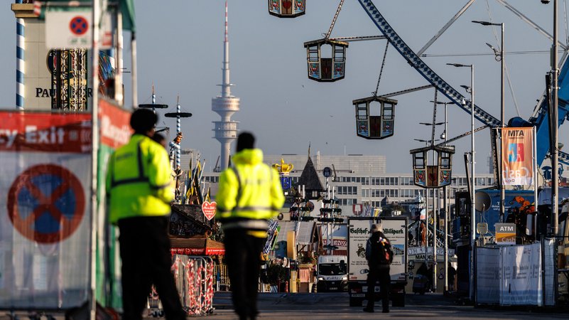 02.10.2025, Bayern, München: Sicherheitspersonal steht am Morgen vor der Öffnung des Oktoberfests für Besucher an einem Eingang vom Oktoberfestgelände, während Mitarbeiter und Zulieferer das Gelände betreten. | Bild: dpa-Bildfunk/Matthias Balk 02.10.2025, Bayern, München: Sicherheitspersonal steht am Morgen vor der Öffnung des Oktoberfests für Besucher an einem Eingang vom Oktoberfestgelände, während Mitarbeiter und Zulieferer das Gelände betreten.