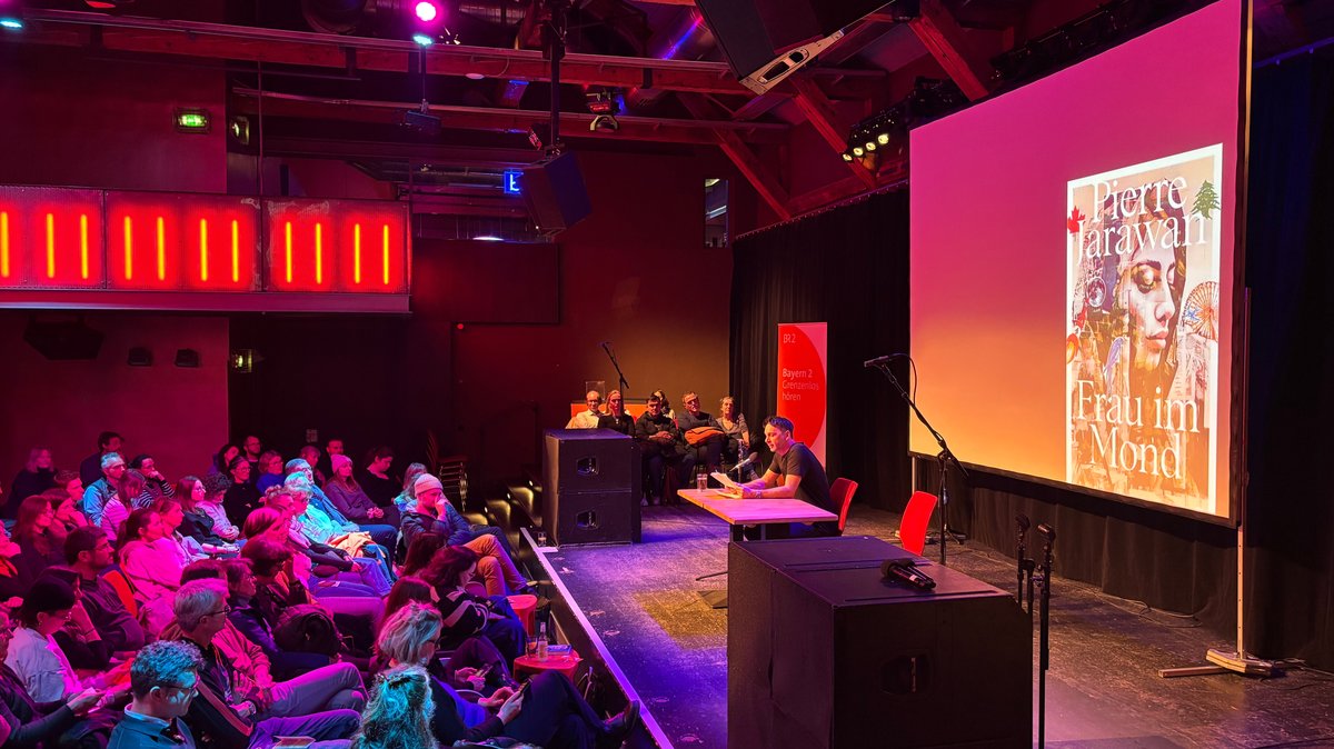 Pierre Jarawan liest im Muffatwerk München, beim Festival "Wortspiele", aus seinem Roman "Frau im Mond". Das Publikum folgt der Geschichte aufmerksam.