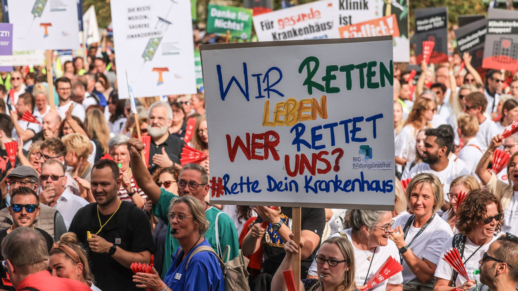 Menschen stehen mit Protest-Plakaten vor dem Brandenburger Tor in Berlin.