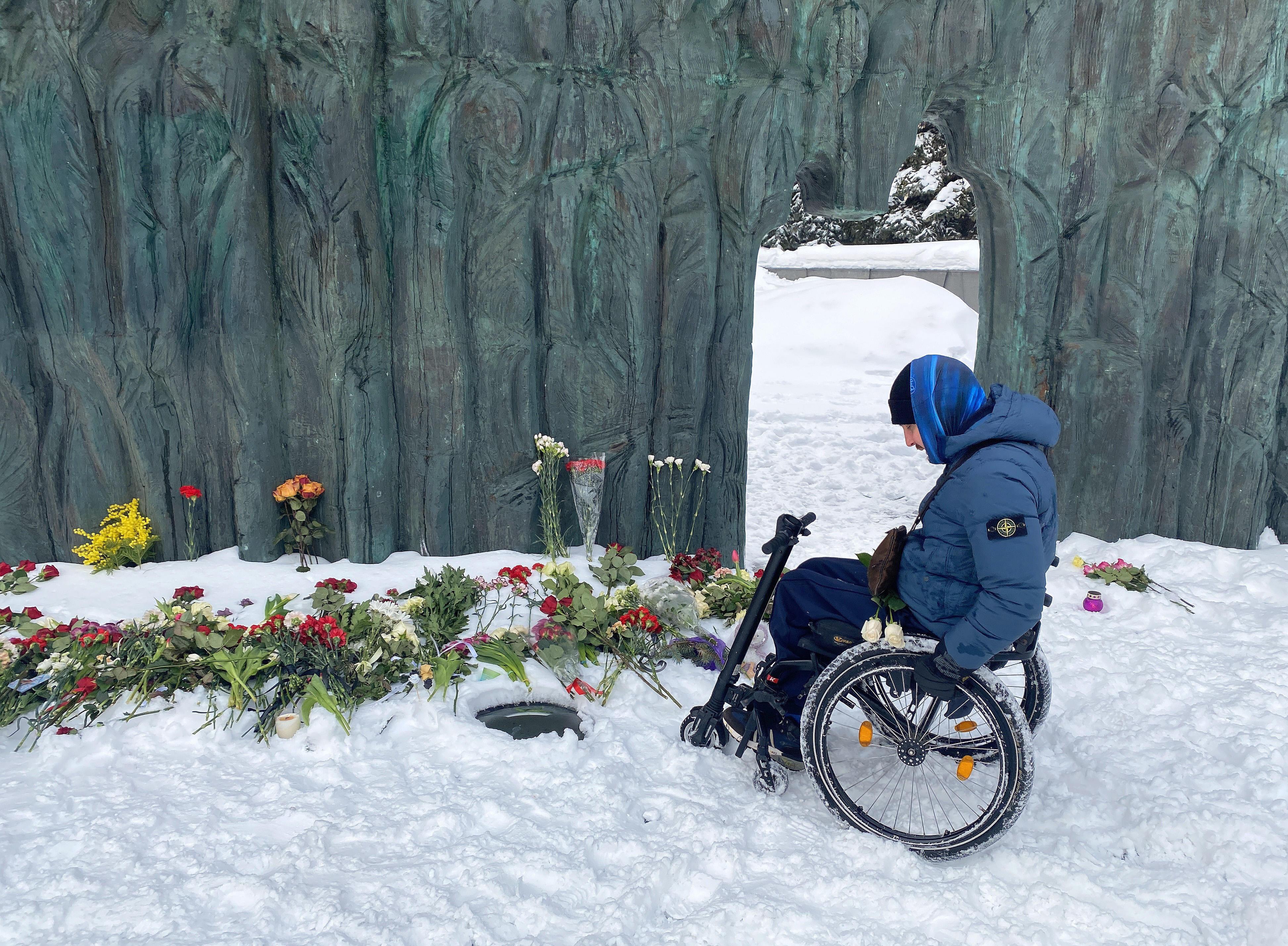 Ein Rollstuhlfahrer legt Blumen nieder