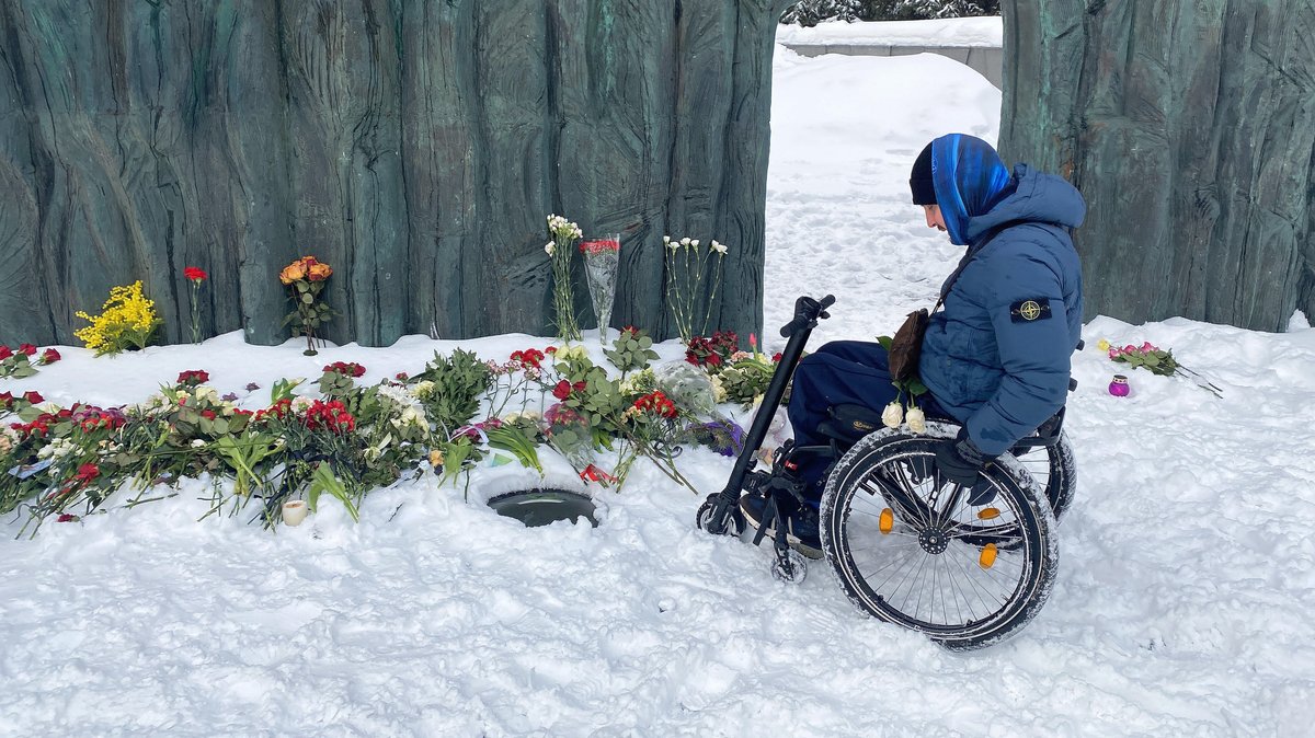 Ein Rollstuhlfahrer legt Blumen nieder