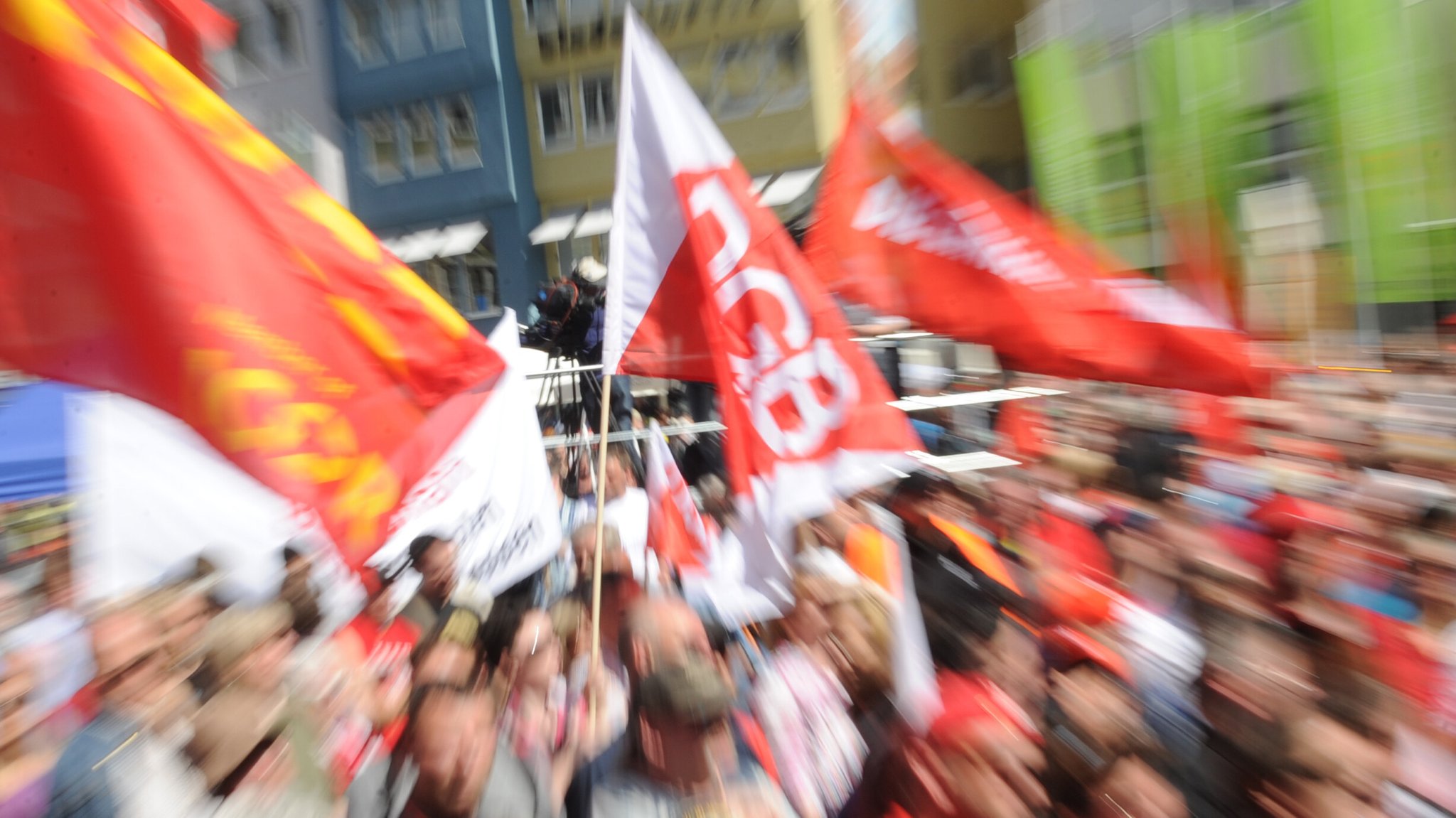 Eine Menschenmenge steht auf einem Platz und schwenkt zum 1. Mai Flaggen, auf denen unter anderem das Logo des DGB zu sehen ist. | Bild: picture alliance / dpa | Franziska Kraufmann Eine Menschenmenge steht auf einem Platz und schwenkt zum 1. Mai Flaggen, auf denen unter anderem das Logo des DGB zu sehen ist.