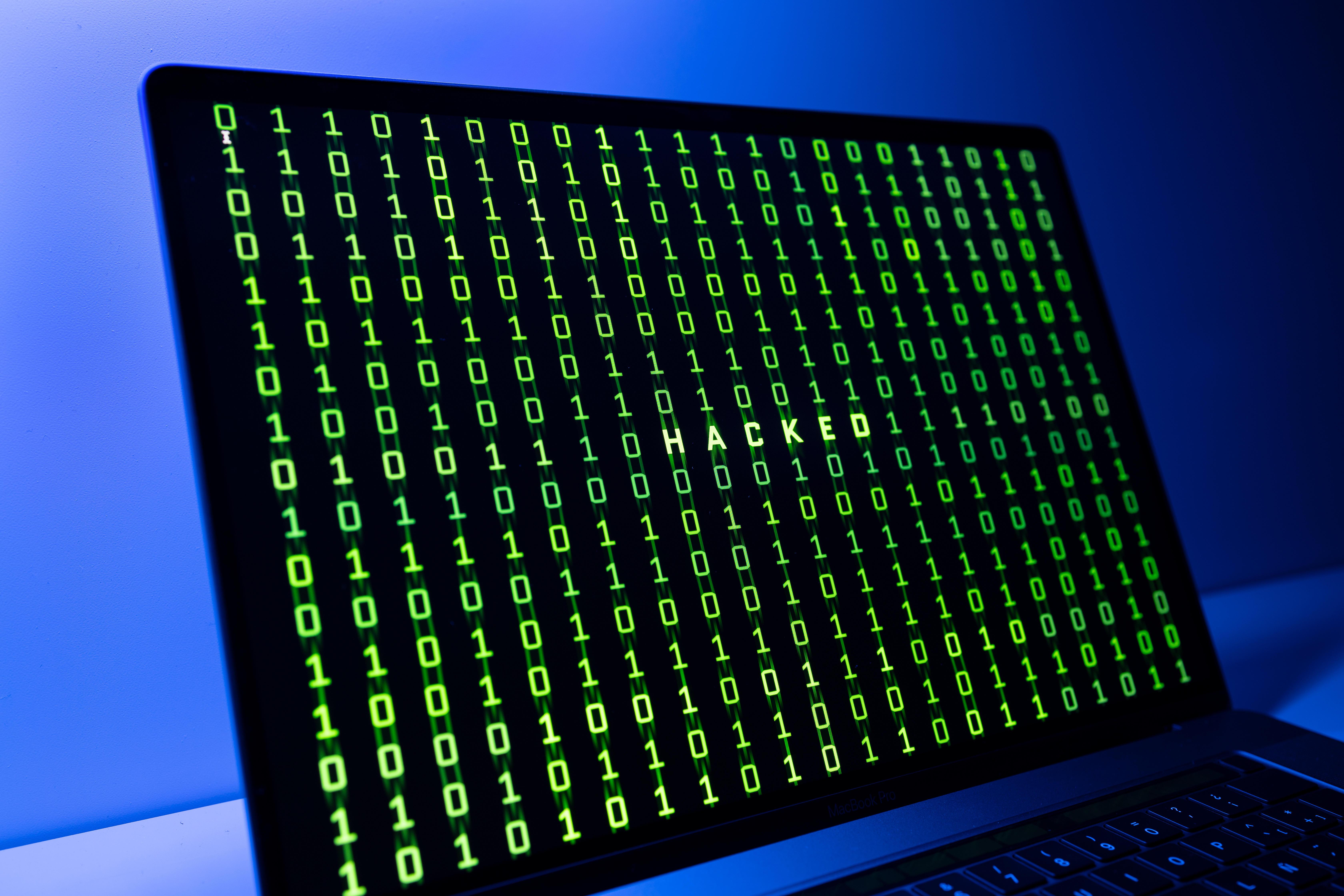 Symbolbild: Ein Bildschirm mit einem Binärcode und dem Wort Hacked. 