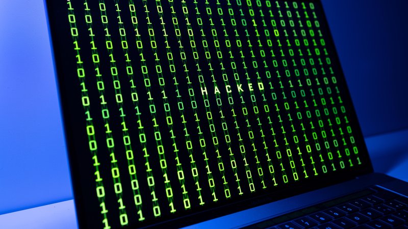 Symbolbild: Ein Bildschirm mit einem Binärcode und dem Wort Hacked. | Bild: picture alliance / Zoonar | Andres Victorero Symbolbild: Ein Bildschirm mit einem Binärcode und dem Wort Hacked.