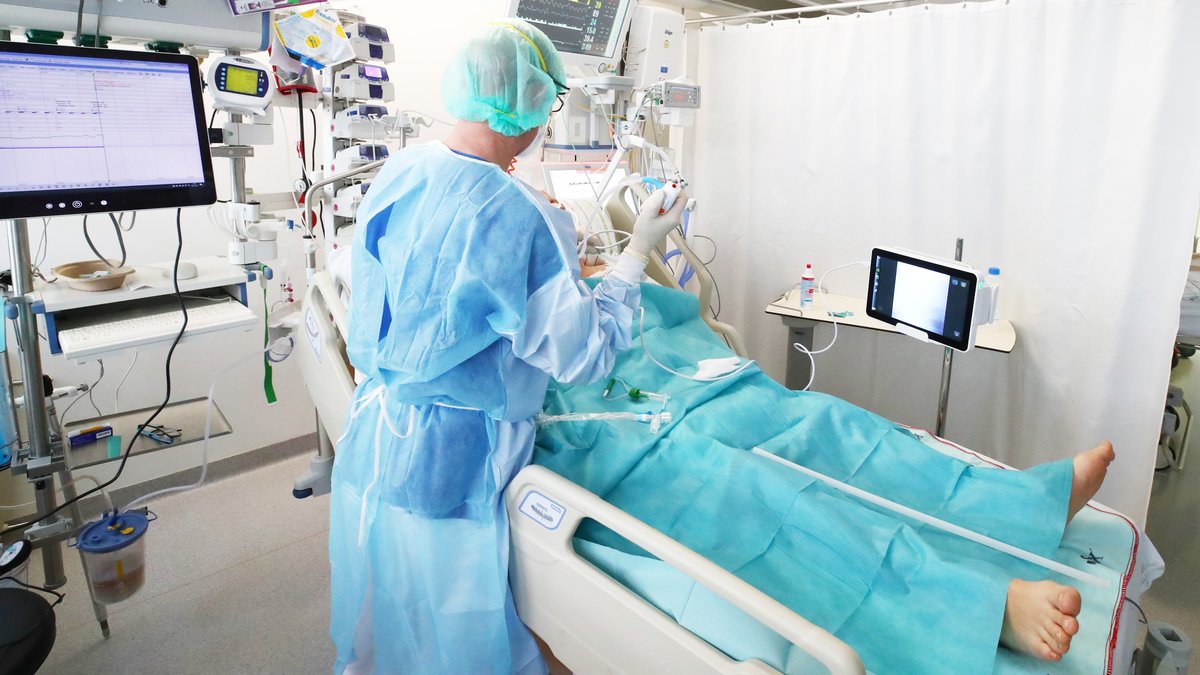 Ärzte und Pfleger untersuchen einen Patienten auf der Covid-19 Intensivstation