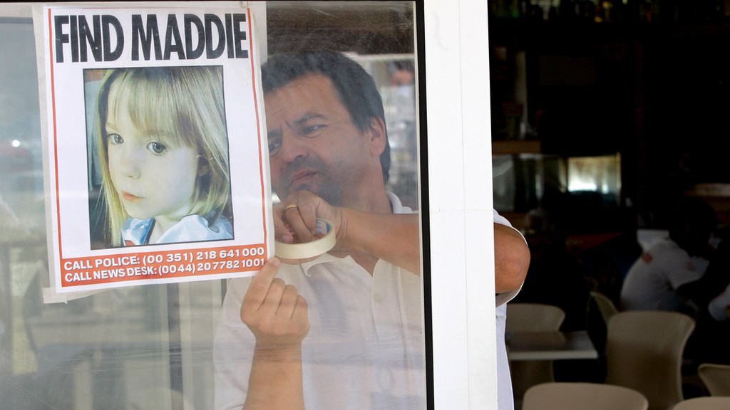 Ein Mann klebt 2007 ein Bild von Maddie McCann ins Fenster.