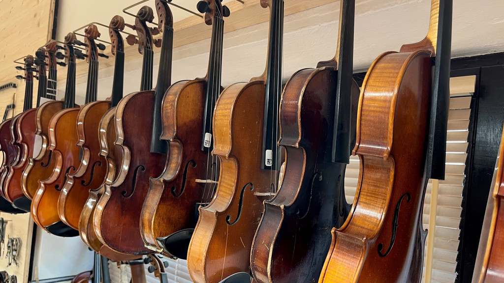 Geigen und Bratschen hängen in einer Werkstatt.