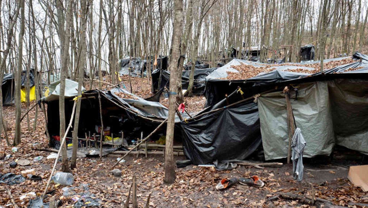 Das Bild zeigt ein wildes Lager in Nordwestbosnien. Aus Planen und mit Stöcken haben sich die menschen improvisierte Zelte gebaut.