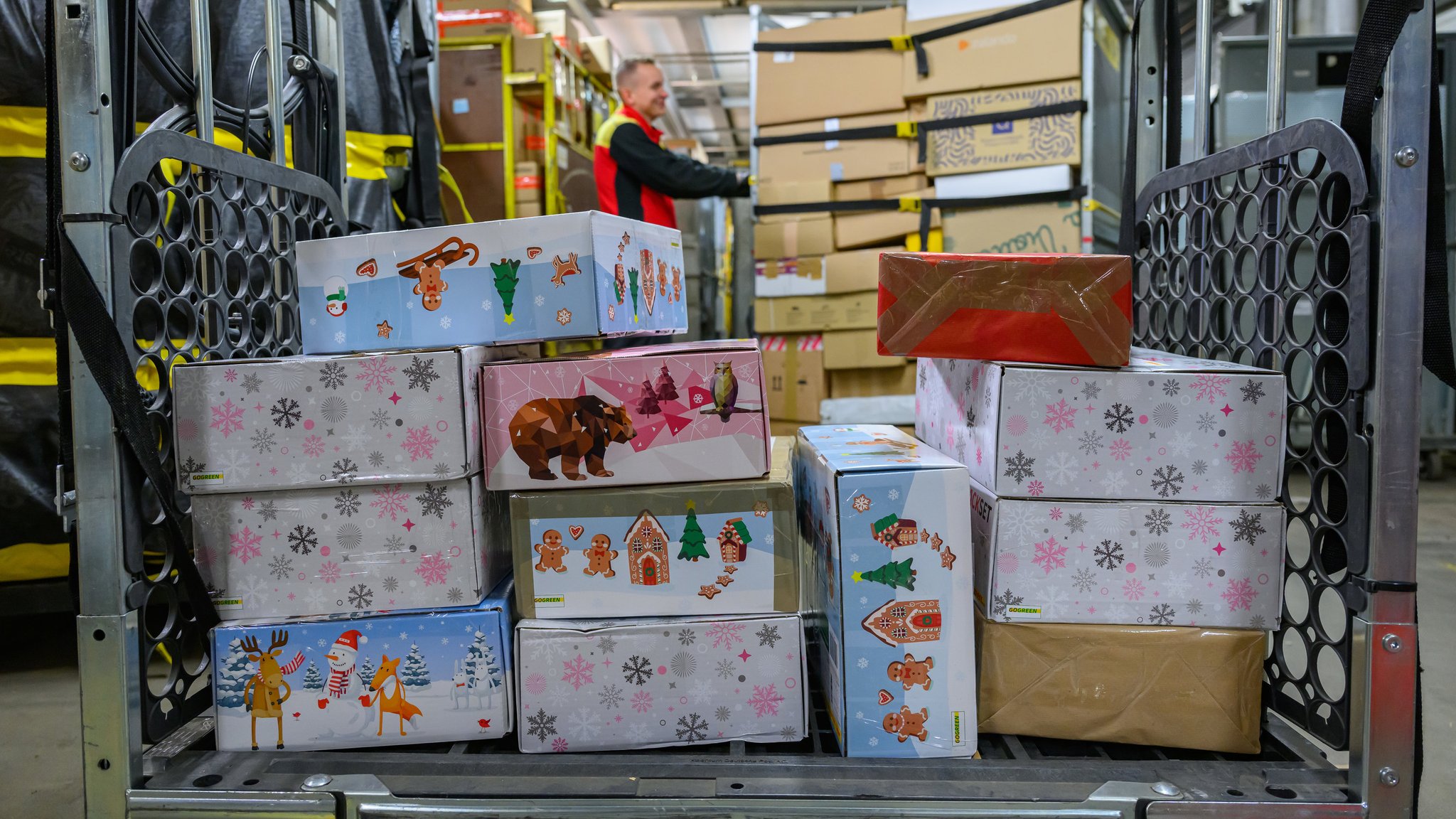 Ein Mitarbeiter transportiert im DHL-Paketzentrum Transportwagen voller Päckchen und Paketen.