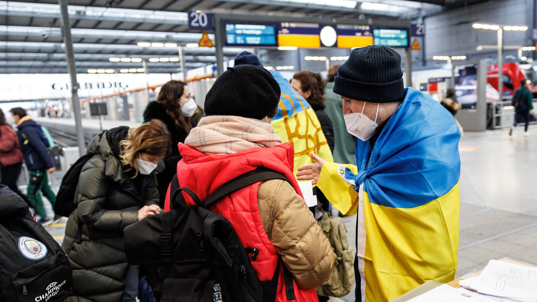 Ein ukrainisch sprechende Helfer (r) spricht an einem Info-Point am Münchner Hauptbahnhof für geflüchtete Ukrainer mit einer Ukrainerin. Kriegsflüchtlinge werden an der zentralen Anlaufstelle von der Caritas, der Landeshauptstadt München und dem Netzwerk „Willkommen in München“ mit zahlreichen Ehrenamtlichen unterstützt.