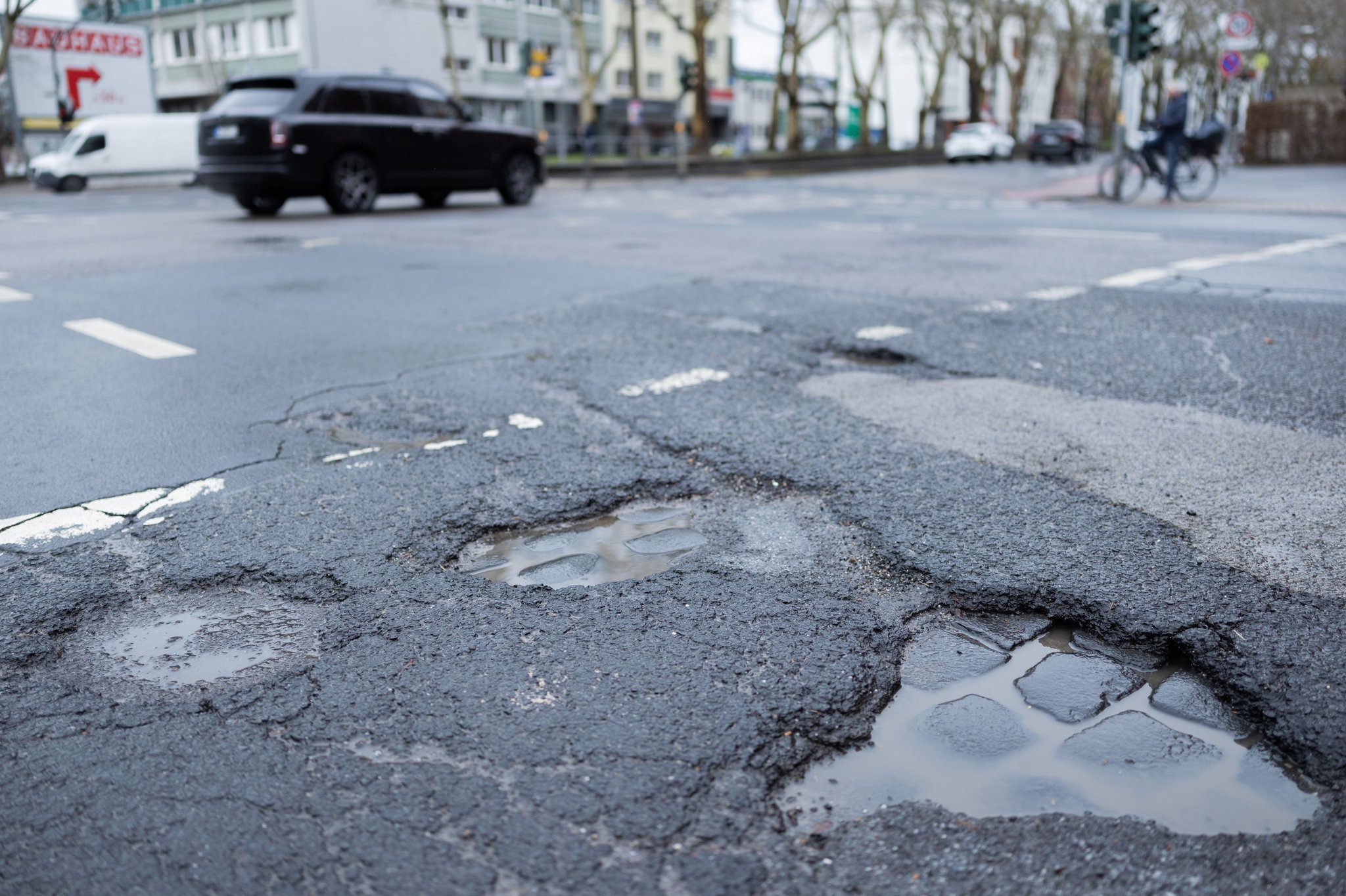 Autos fahren auf einer Straße mit Schlaglöcher. Foto: Rolf Vennenbernd/dpa +++ dpa-Bildfunk +++