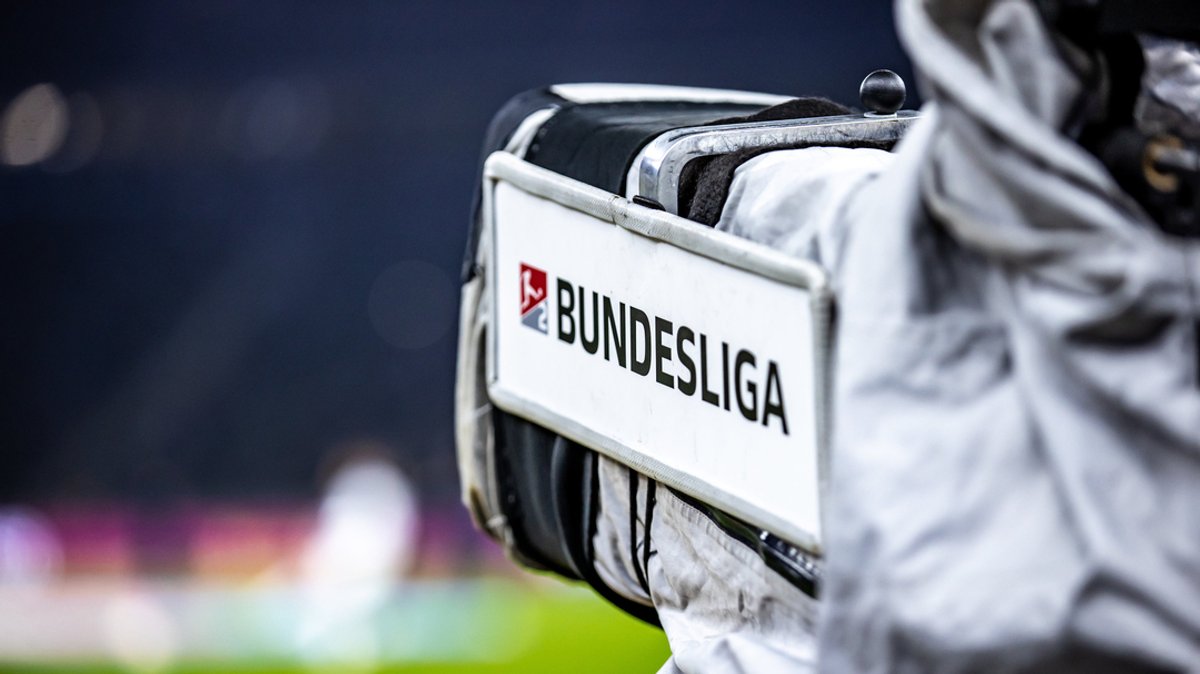 Eine Kamera mit Schriftzug "Bundesliga" ist auf einen Fußball-Platz gerichtet.