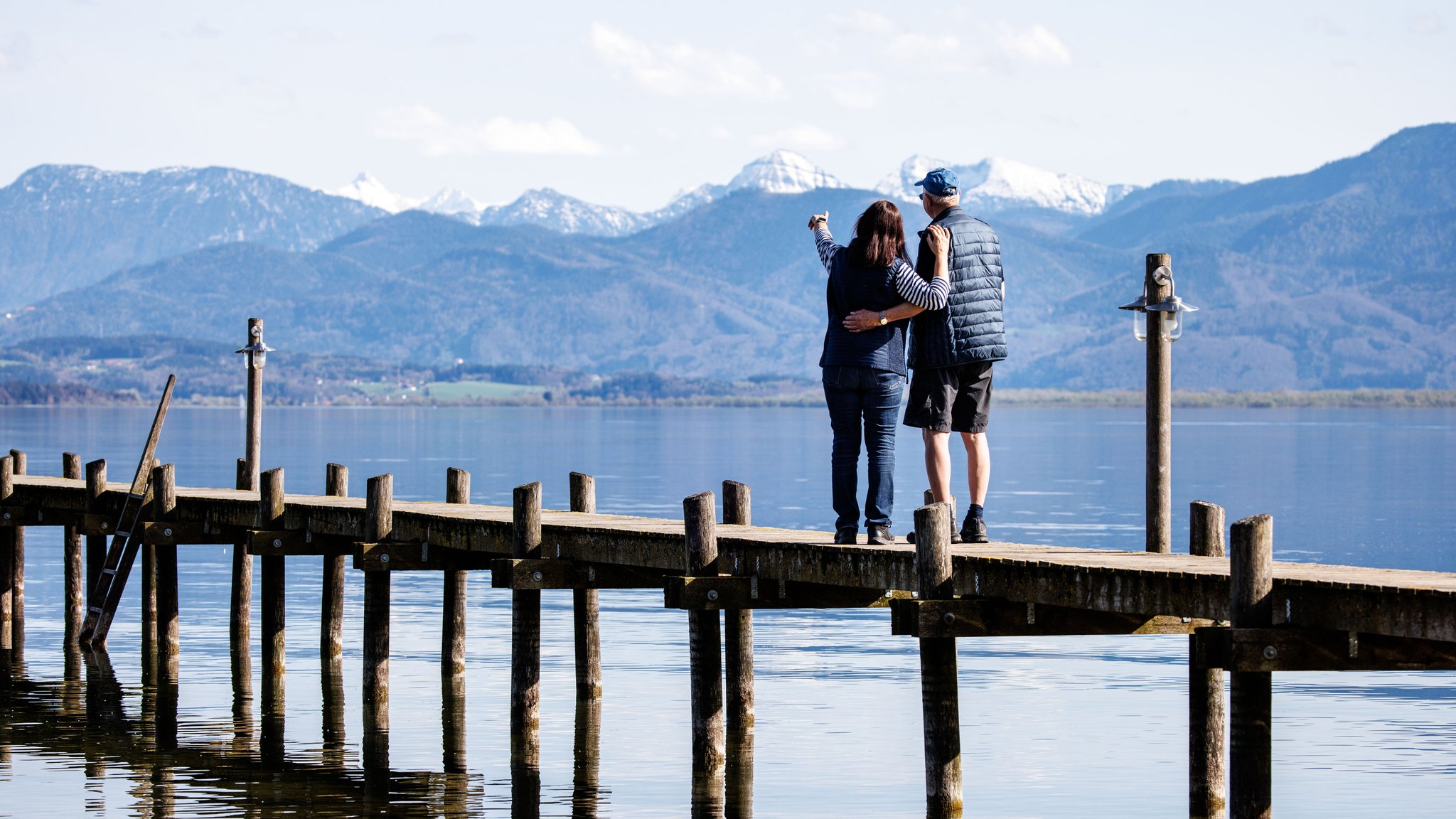 Ein Mann und eine Frau stehen gemeinsam auf einem Steg am Chiemsee