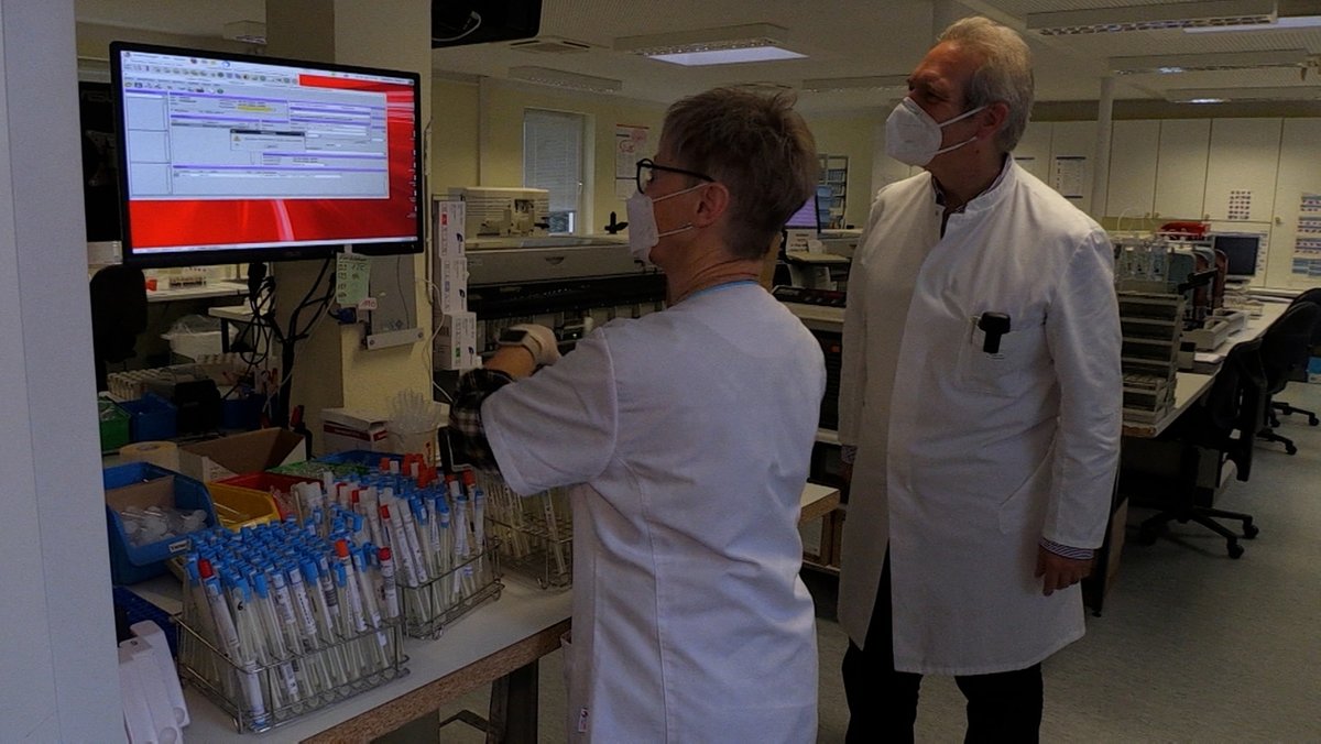 Zwei Mitarbeiter im AllgäuLab blicken auf einen Bildschirm, darunter stehen viele Teströhrchen.