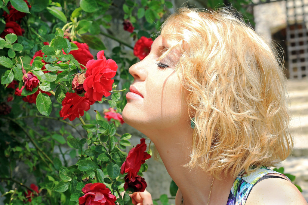 Eine Frau riecht an einer duftenden Rosenblüte: Mit SARS-CoV-2-Infizierte können offenbar einige Zeit nichts oder wenig riechen.