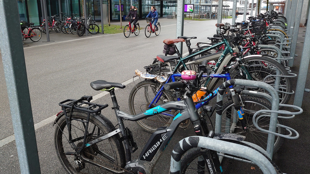 Ein voller Radlständer und zwei Radfahrerinnen bei Roche in Penzberg