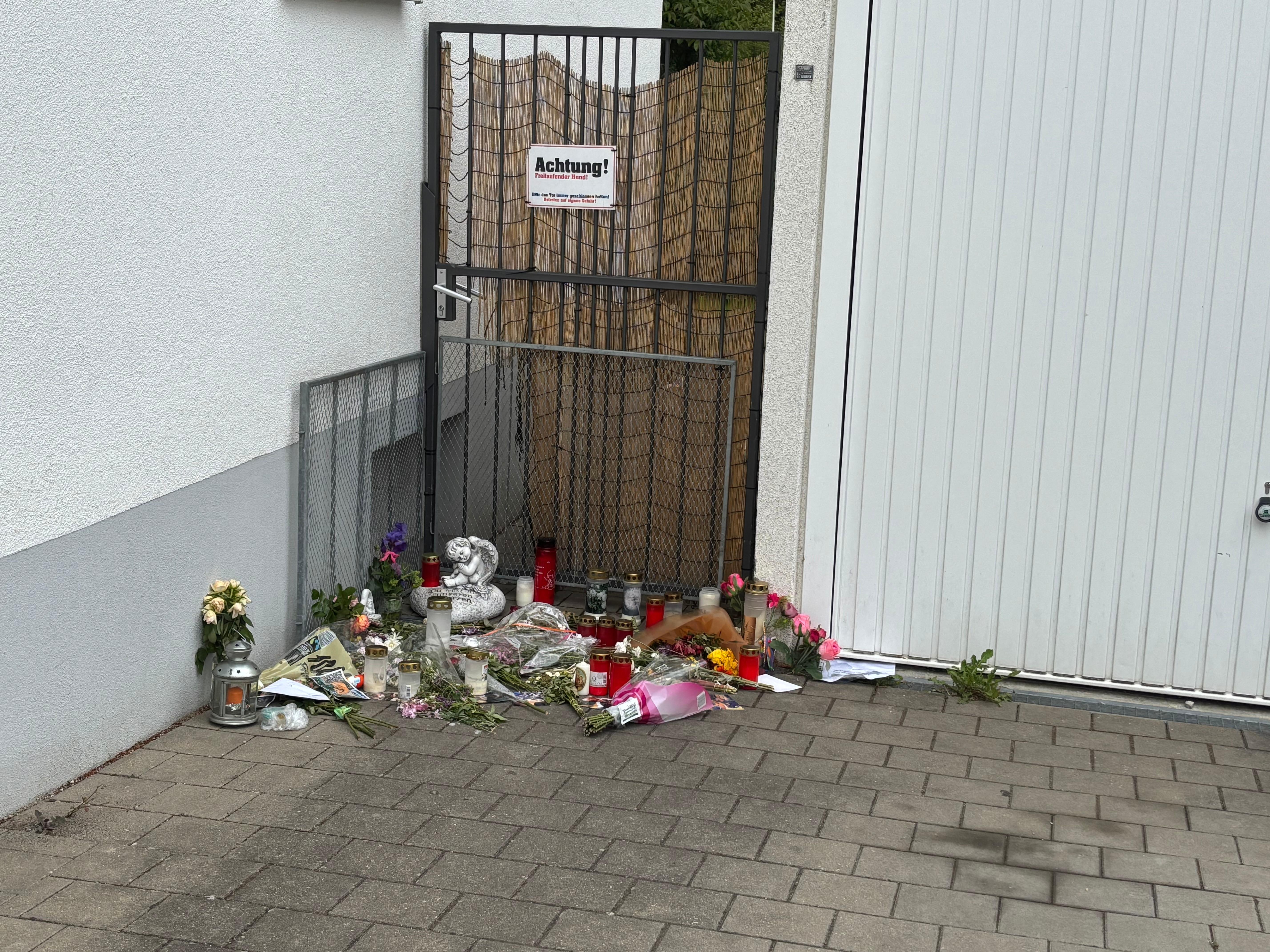 Vor dem Wohnhaus der getöteten Mutter legten Menschen Kerzen, Blumen und eine kleine Engelsfigur nieder.