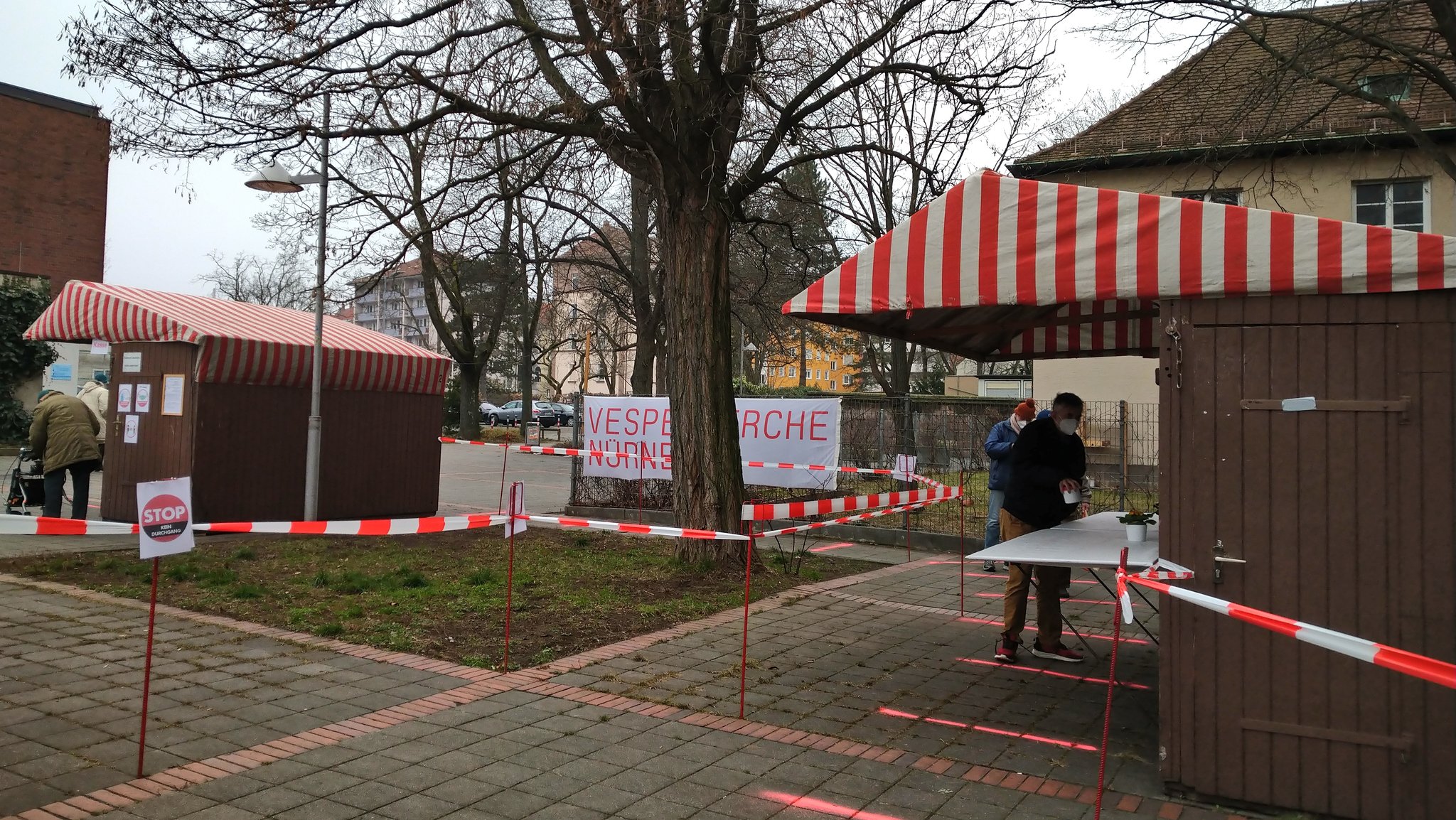 In Holzbuden vor der Kirche holen sich Menschen ein warmes Mittagessen ab.