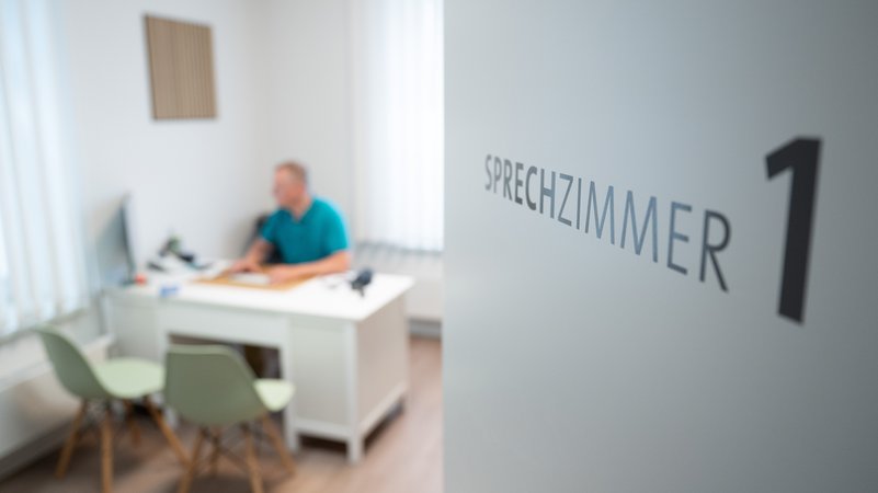 Ein Hausarzt sitzt in einem Sprechzimmer seiner Hausarztpraxis an einem Schreibtisch und arbeitet am Computer. | Bild: picture alliance/dpa | Sebastian Kahnert Ein Hausarzt sitzt in einem Sprechzimmer seiner Hausarztpraxis an einem Schreibtisch und arbeitet am Computer.
