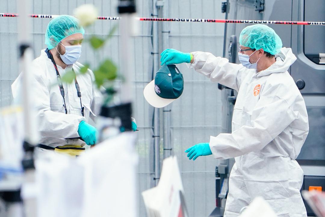 Mitarbeiter der Spurensicherung halten an einem Stand auf dem Marktplatz von Mannheim eine Kappe in den Händen.