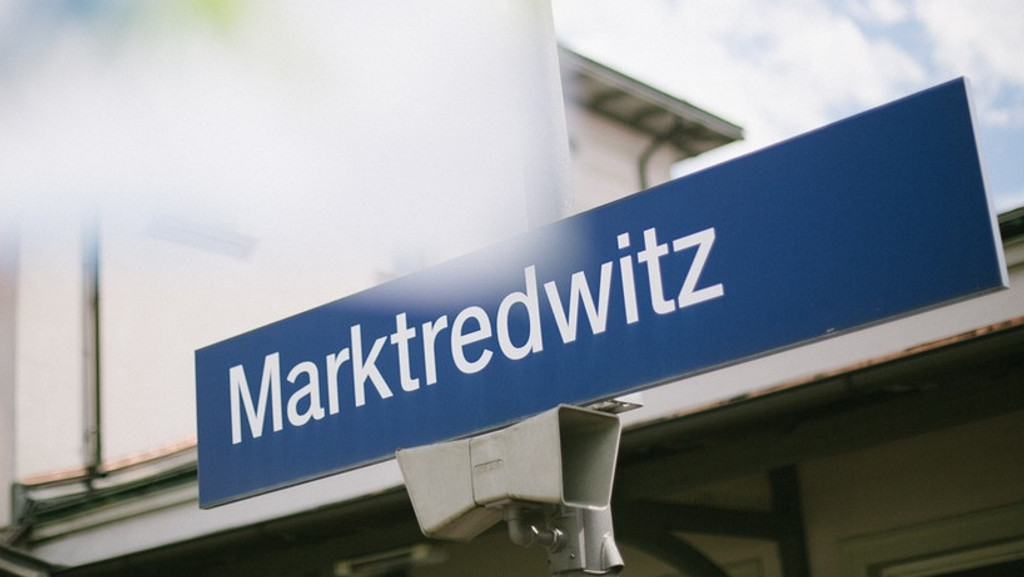 Ein blaues Schild mit Aufschrift "Marktredwitz" am Bahnhof. 