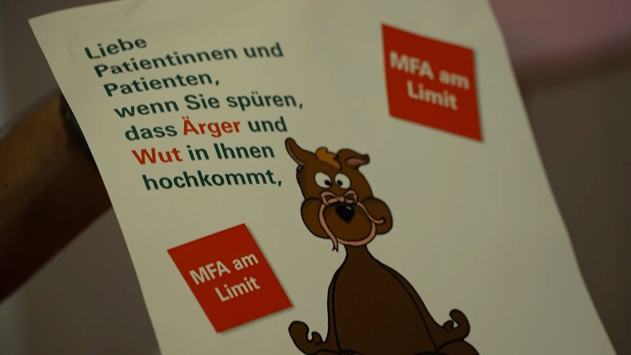 Ein Plakat mit einem meditierenden Tier über dem steht: "Liebe Patientinnen und Patienten, wenn Sie spüren, dass Ärger und Wut in Ihnen hochkommt," und "MFA am Limit".