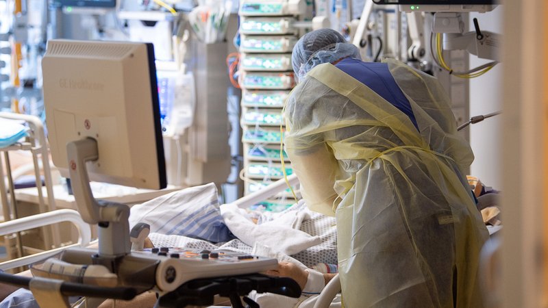 Ein Intensivpfleger steht auf der Intensivstation eines Krankenhauses neben einem Covid-19-Patienten.
